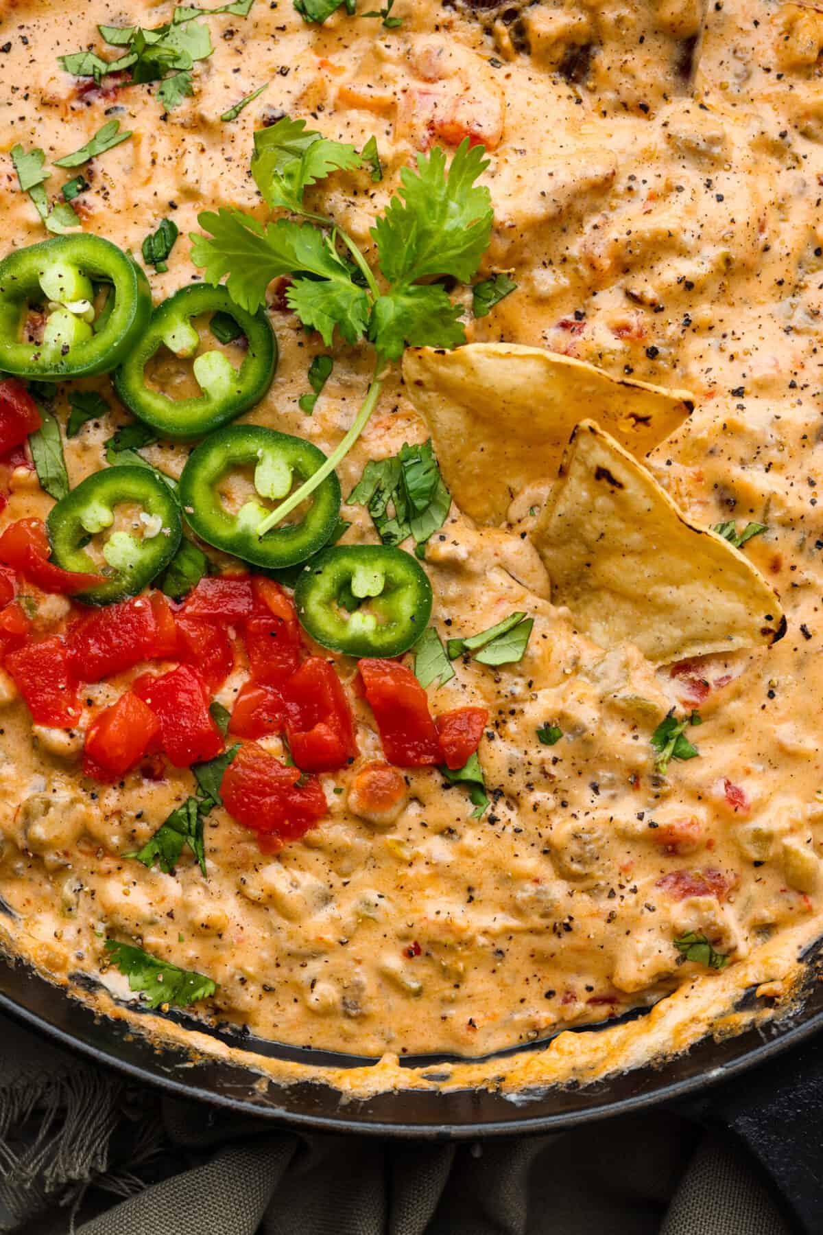 Sausage dip is a must-make appetizer for any potluck, party, or get-together! Crumbled sausage, cream cheese, pepper jack, chopped tomatoes and green chiles get cooked together to melty perfection. Closeup of sausage dip with tortilla chips in it.