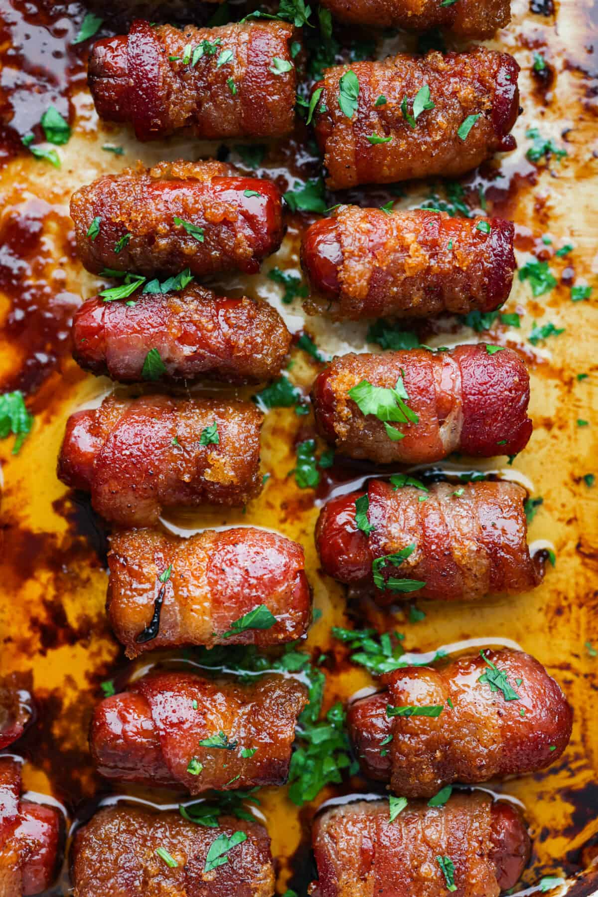 These bacon wrapped smokies are the perfect sweet and salty appetizer that everyone will devour! Little smokie sausagesย are wrapped in crispy bacon and caramelized in a brown sugar spice blend. They are sure to be a favorite at your next party! Top view of bacon wrapped smokies in a baking dish.