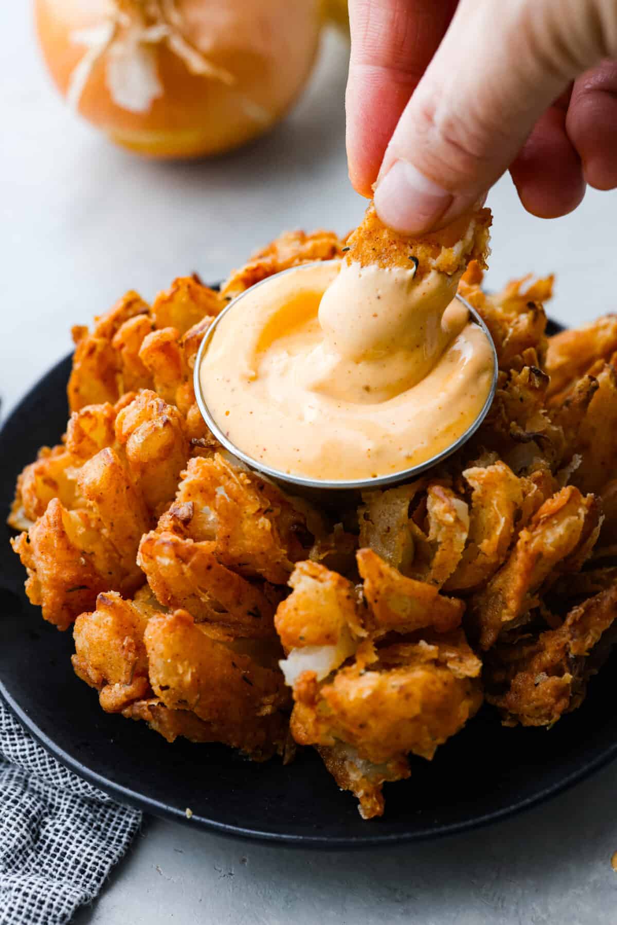 The best of the best when it comes to appetizers, this crispy bloomin' onion is the best addition to any meal. Each onion is coated in a seasoned buttermilk breading that will have you reaching for another piece. Dipping a piece of onion into a creamy sauce.