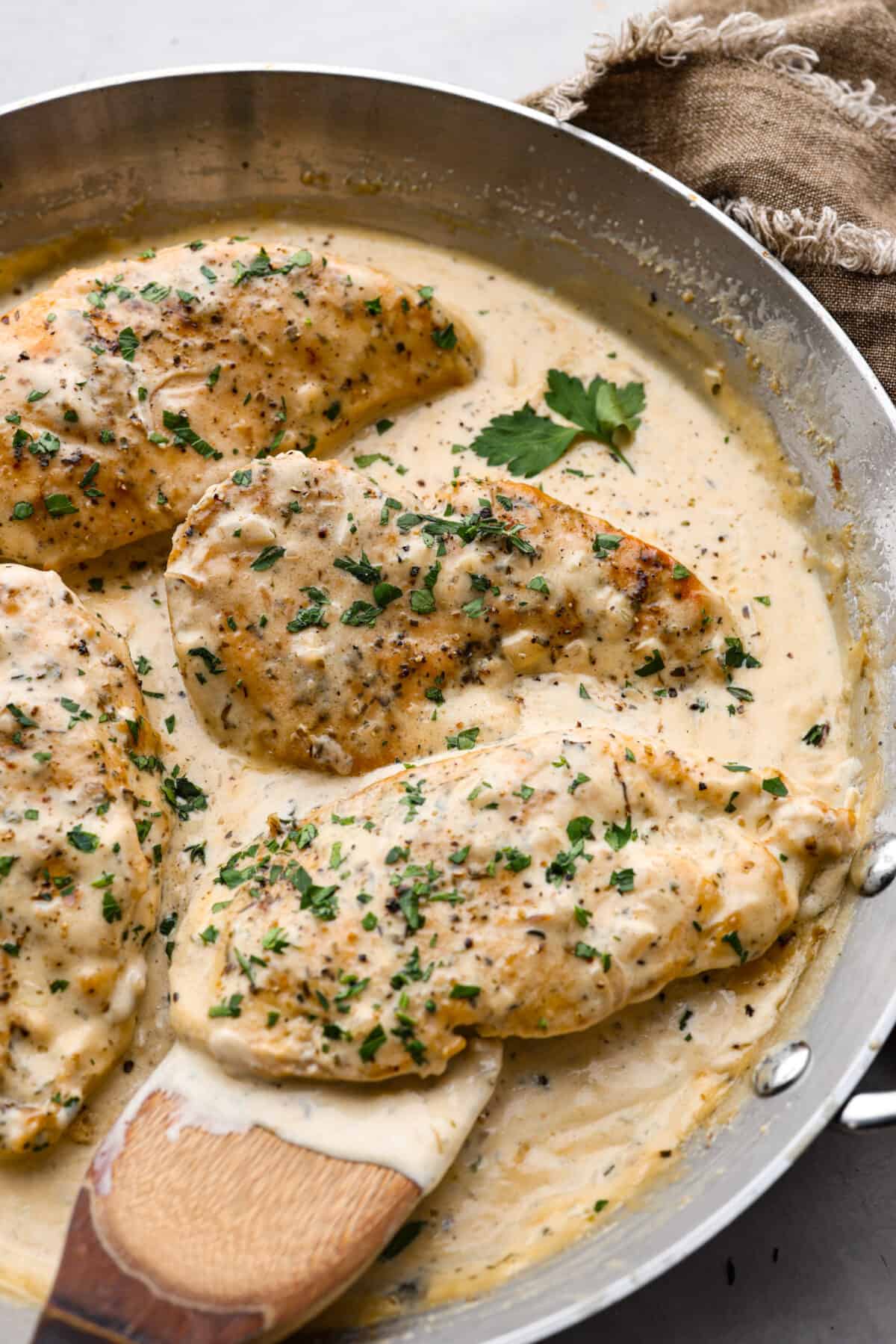 Creamy Boursin Chicken is a rich and decadent one-pan dish that is ready in just about 30 minutes! Pan-fried, seasoned chicken is smothered in a delicious sauce made with cream, parmesan cheese and Boursin cheese. 4 pieces of boursin chicken in a metal pan.