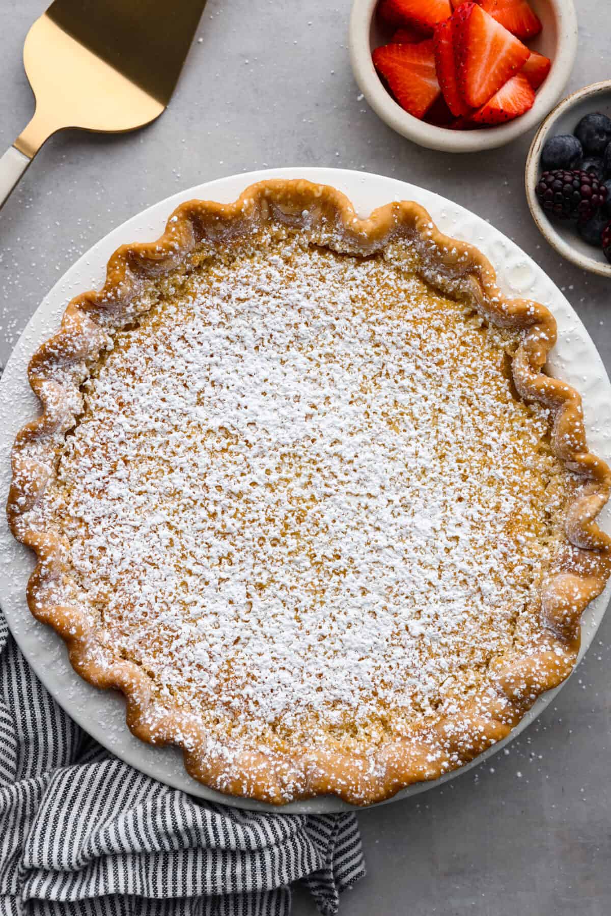 This amazing buttermilk pie is made with a creamy, lemon-kissed custard tucked inside a buttery, golden crust. So delicious and perfect for any time of year. It's like sunshine in pie form! Top-down view of a whole buttermilk pie.