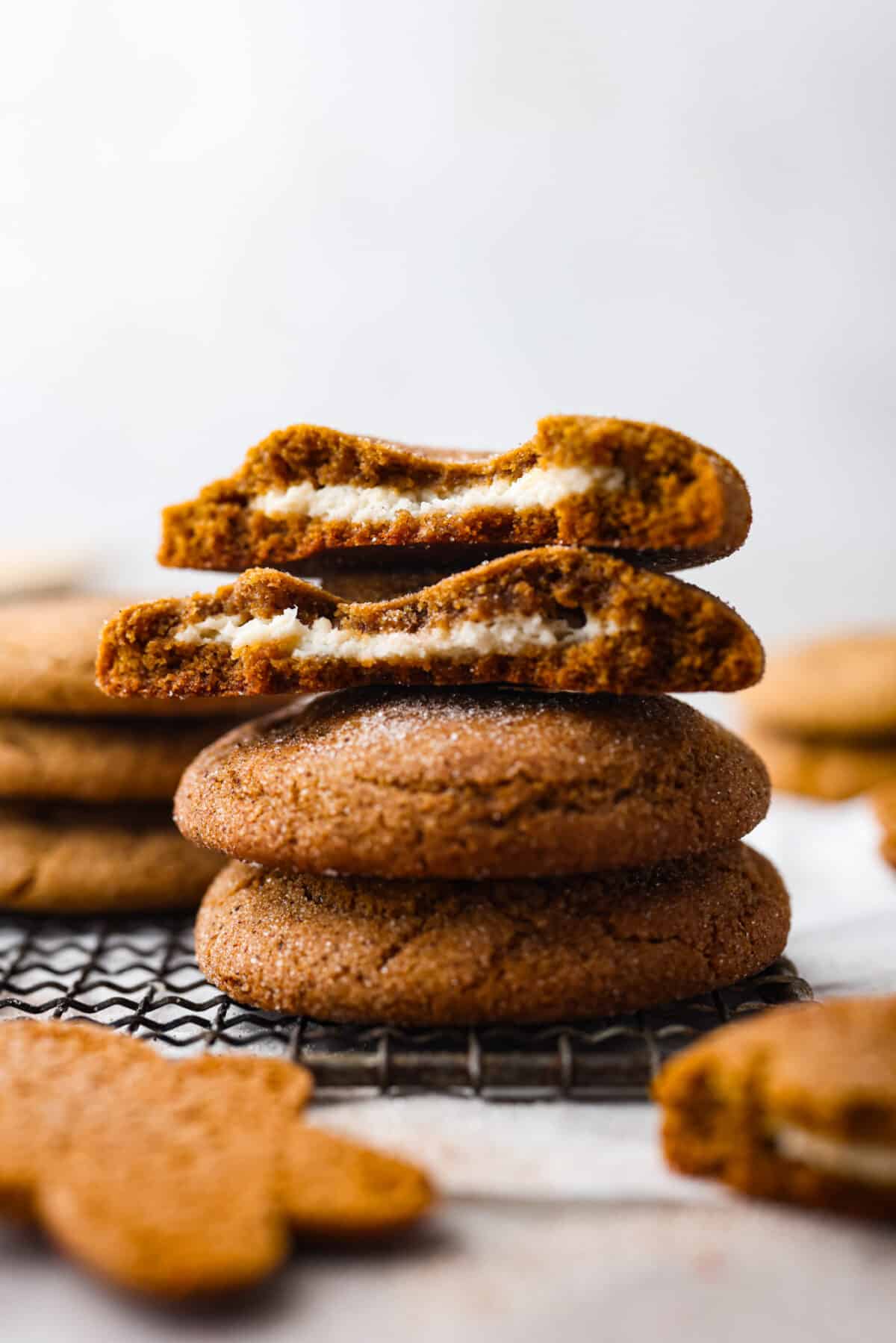 A fun twist on a holiday favorite! These cheesecake stuffed gingerbread cookies are soft and spiced to perfection, filled with a rich and creamy filling. Each bite is a dream! 4 stuffed gingerbread cookies stacked on top of each other. 2 are ripped in half so the filling can be seen.