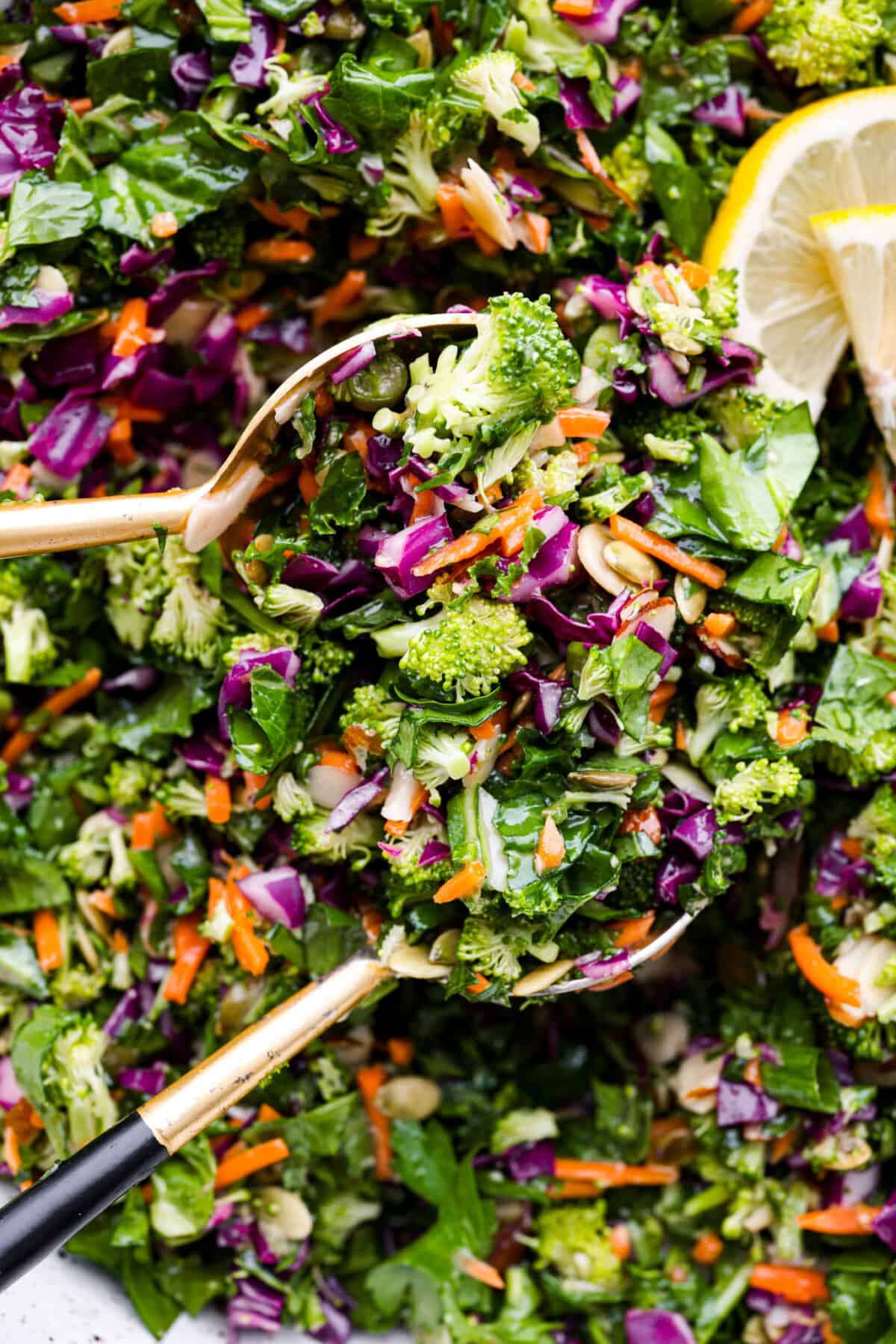 This healthy and colorful detox salad is LOADED with lots of greens and fresh veggies. The added nuts and seeds give a delicious crunch and texture to the salad. Drizzled with a lemon ginger vinaigrette, this salad has so many vibrant flavors! Close view of serving spoons lifting up a scoop of salad.