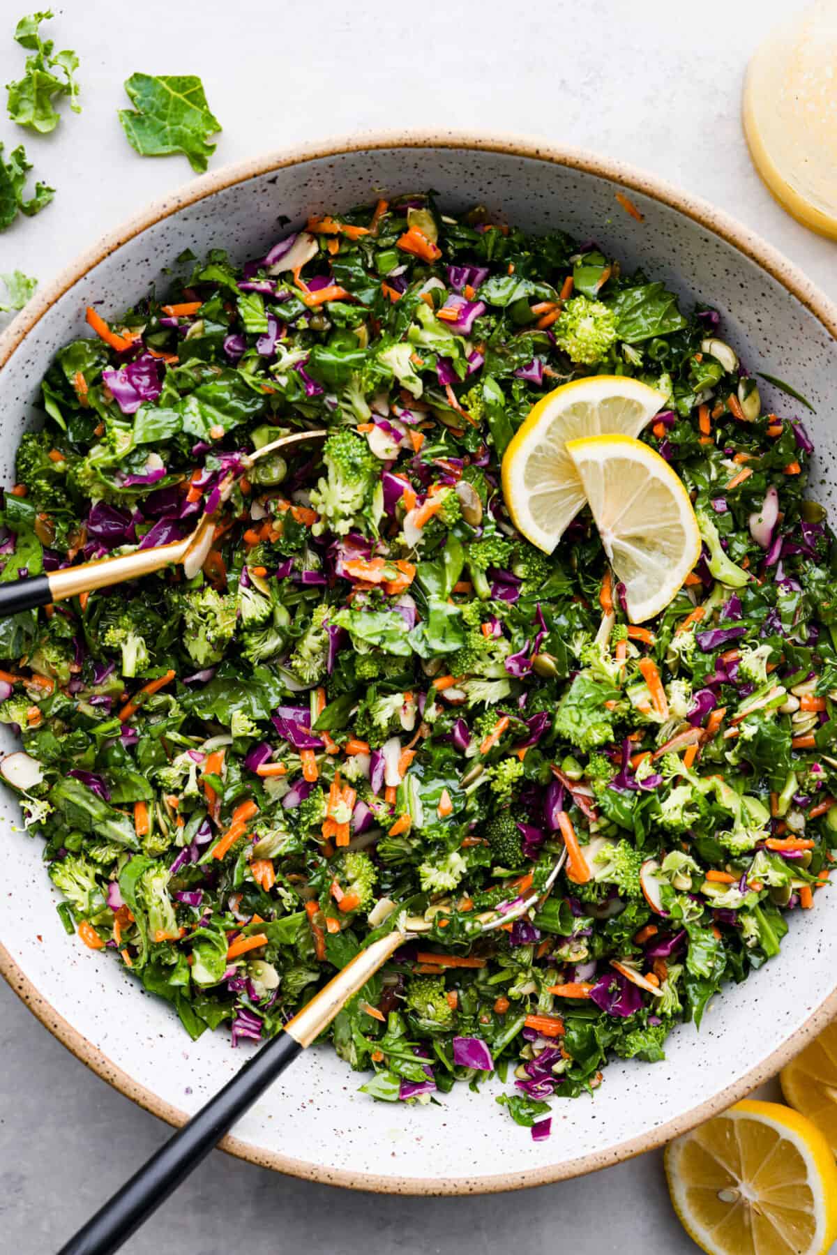 This healthy and colorful detox salad is LOADED with lots of greens and fresh veggies. The added nuts and seeds give a delicious crunch and texture to the salad. Drizzled with a lemon ginger vinaigrette, this salad has so many vibrant flavors! Overhead view of detox salad in a large bowl with a serving spoon.