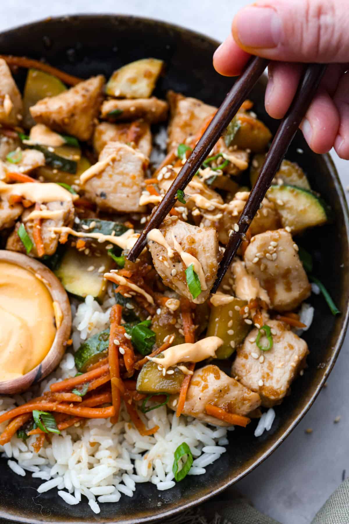 Seared to golden perfection in a savory sauce, you're going to love enjoying this hibachi chicken from the comfort of your kitchen! Picking up hibachi chicken with chopsticks.