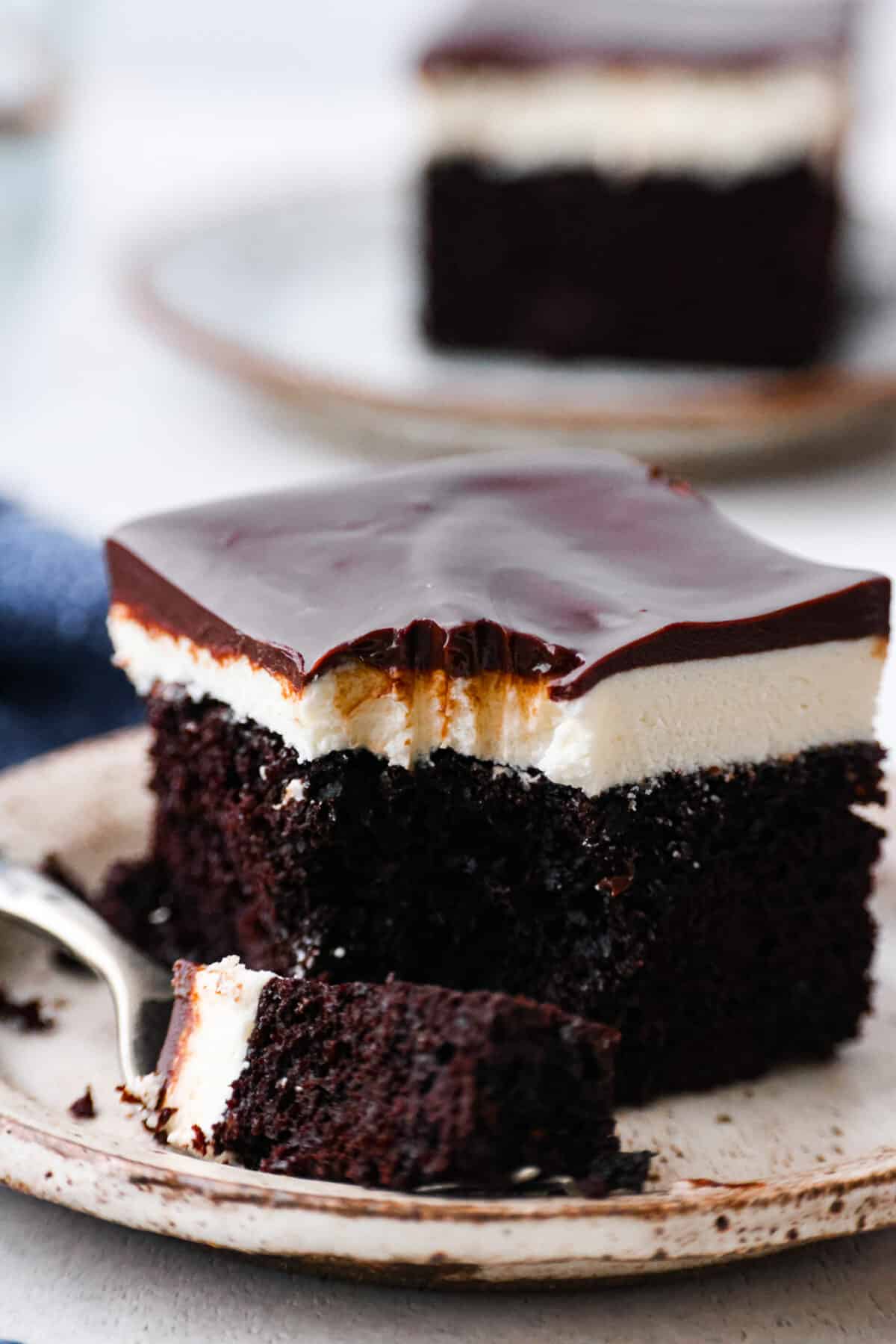 Transform your favorite childhood snack cake into a decadent ho ho cake. Inspired by a Hostess ho hos, this dark chocolate cake is topped with cream filling and fudgy ganache frosting. Every bite takes you back to feeling like a kid again! Close view of a fork on a plate with a slice of ho ho cake.