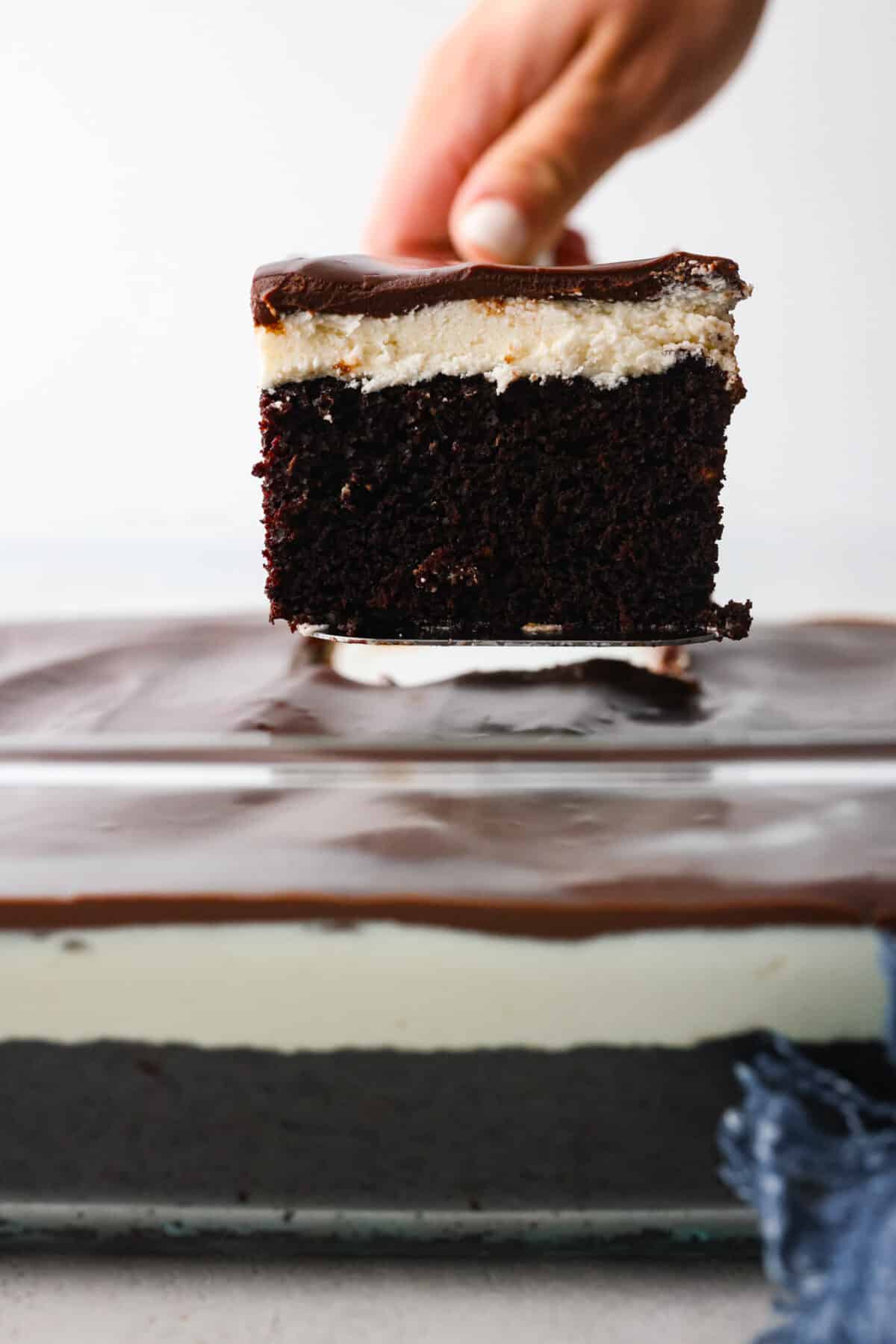 Transform your favorite childhood snack cake into a decadent ho ho cake. Inspired by a Hostess ho hos, this dark chocolate cake is topped with cream filling and fudgy ganache frosting. Every bite takes you back to feeling like a kid again! Close view of a spatula lifting up a slice of ho ho cake.