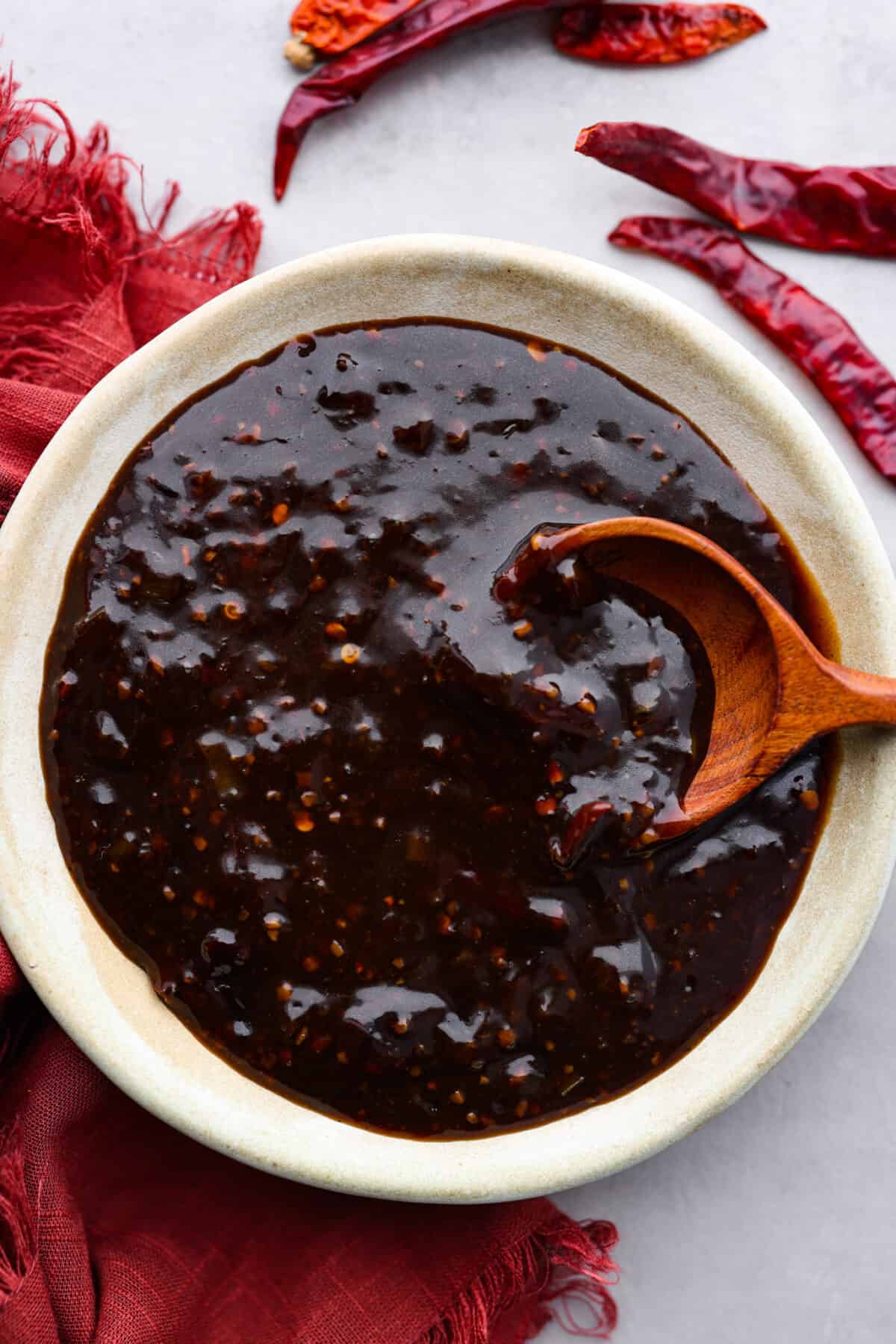 Sweet, sour, and spicy, Kung Pao Sauce is easy to make and the perfect addition for your Chinese-inspired dishes. This homemade version is so flavorful, you'll never want store-bought again! Kung pao sauce in a gray bowl, being stirred with a wooden spoon.