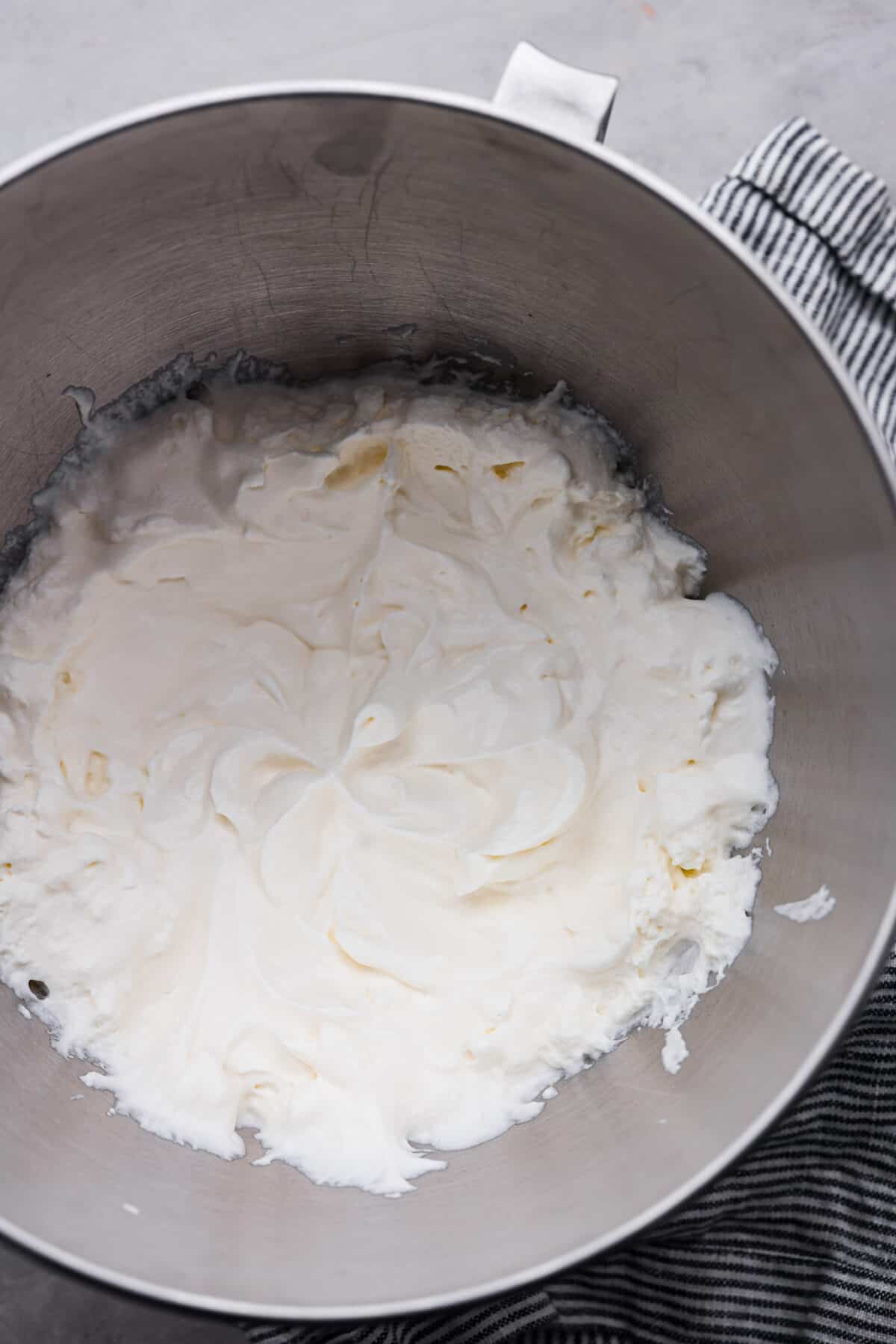 Two of my favorite things combined: marshmallow fluff and fresh whipped cream! It's perfect for adding to your favorite desserts, and is so good, you'll want to eat it straight from the bowl. Top-down view of marshmallow whipped cream in a metal mixing bowl.