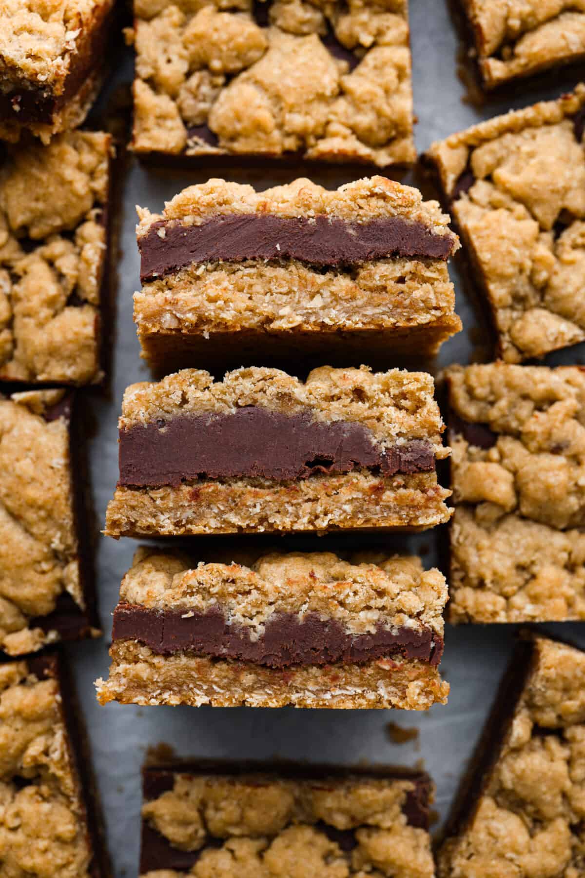 These thick indulgent oatmeal fudge bars left me speechless! Creamy homemade fudge sandwiched between two oatmeal cookie layers. You will love the texture of the oatmeal bars that pairs perfectly with the rich chocolate fudge. Close view of oatmeal fudge bars close together.