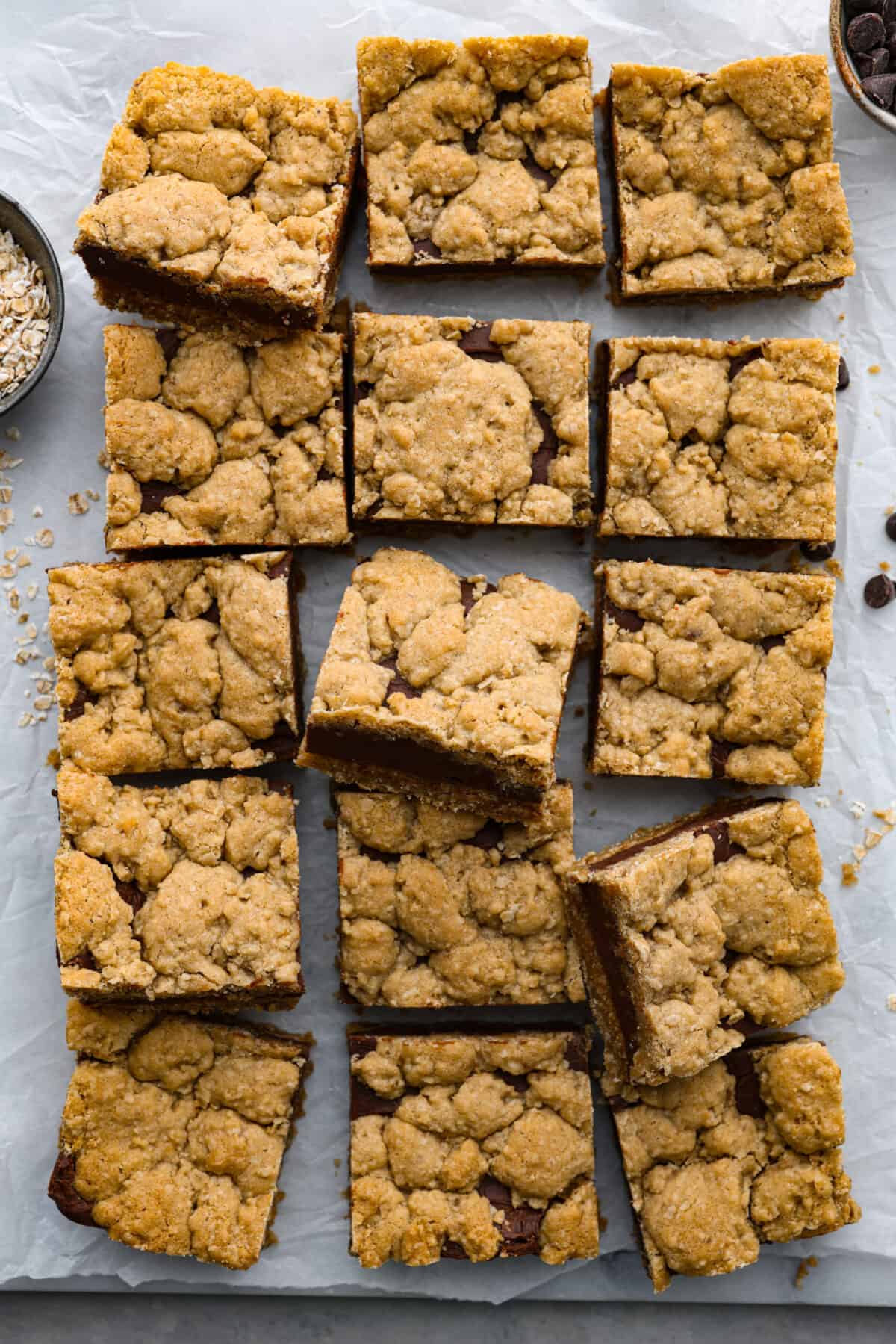 These thick indulgent oatmeal fudge bars left me speechless! Creamy homemade fudge sandwiched between two oatmeal cookie layers. You will love the texture of the oatmeal bars that pairs perfectly with the rich chocolate fudge. Overhead view of cut bars on parchment paper.