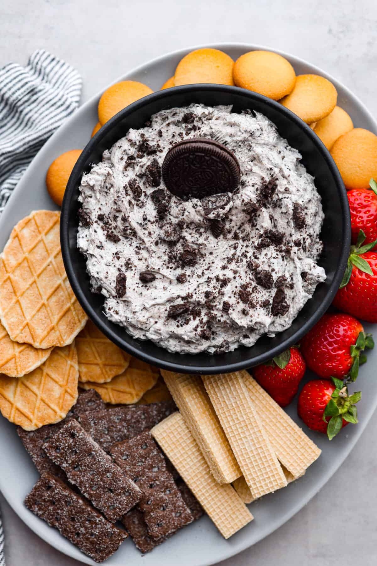 Irresistible, creamy Oreo Dip is an easy, no bake dessert dip with the most wonderful Oreo cookie flavor! Whip this treat up in just 10 minutes with Oreo cookies, cream cheese, powdered sugar, vanilla and Cool Whip. Serve with strawberries and cookies for a fun snack that's sure to be a hit! Cookies and cream dip served with a variety of wafers, cookies, waffle cone pieces, strawberries, and Nilla wafers.