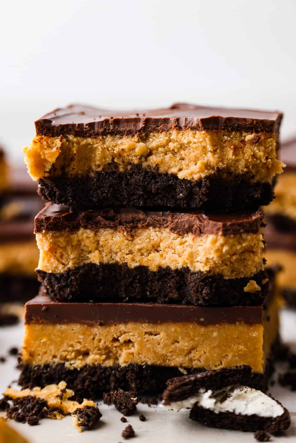 Creamy peanut butter and melted chocolate layered on top of an Oreo crust. What could be better than that? These Oreo peanut butter bars are what dessert dreams are made of! Side shot of a stack of Oreo peanut butter bars with some bites taken out.