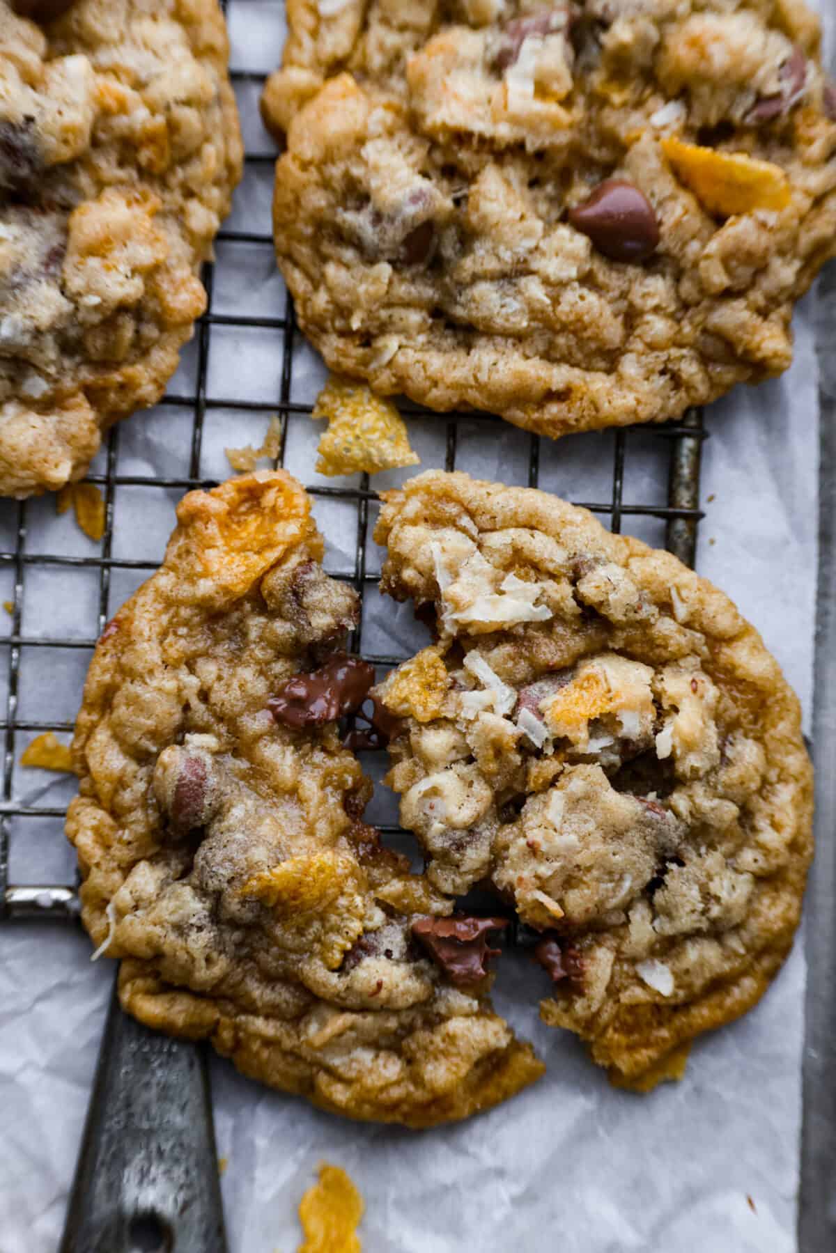 Delicious Ranger Cookies (also called Cowboy Cookies) have slightly crisp edges with soft and chewy centers, and the most wonderful texture. They are filled with hearty oats, crunchy cornflakes, shredded coconut and chocolate chips. You will be blown away by how amazing these cookies taste! Closeup of a cookie broken in half.