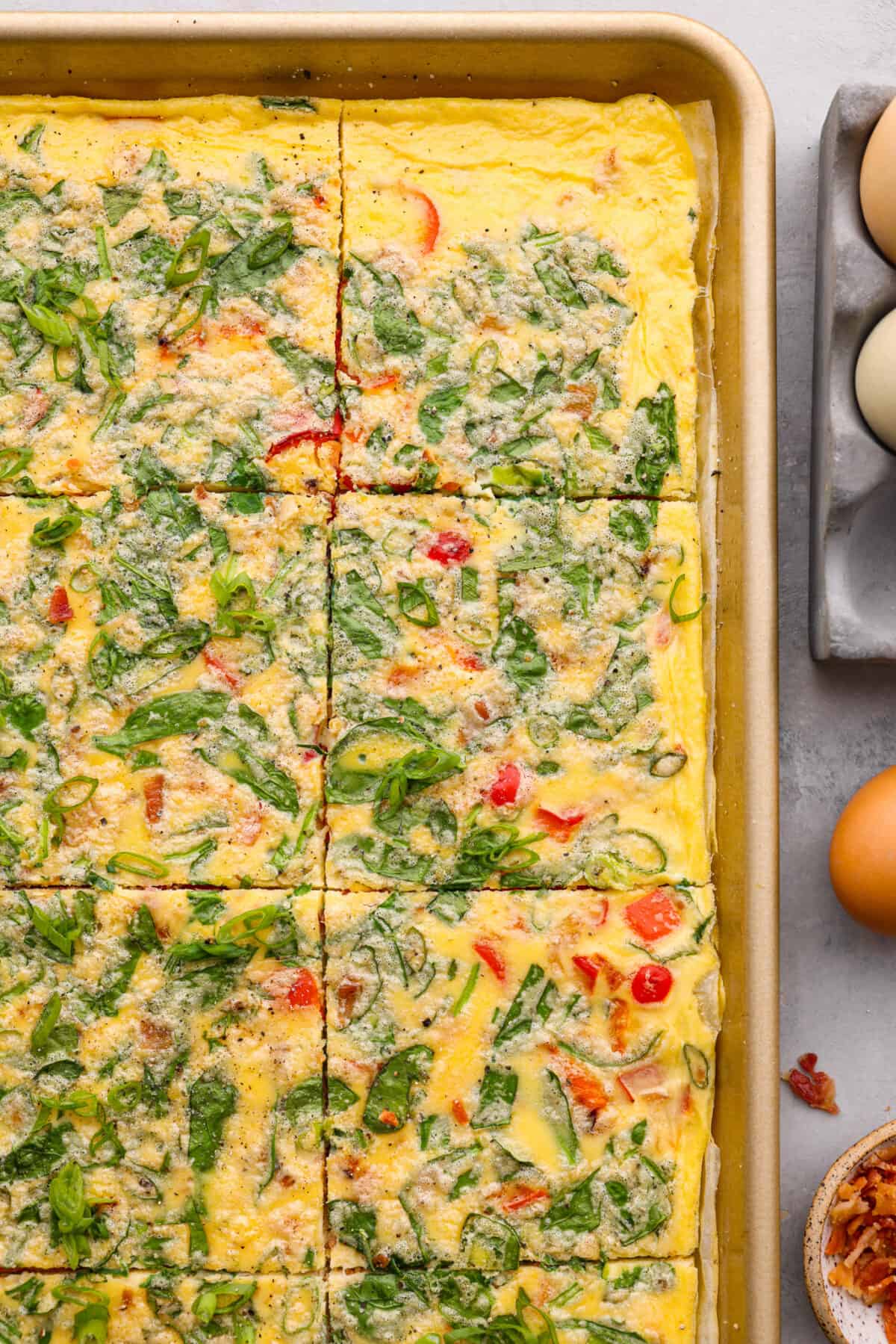 Sheet pan eggs are not only fluffy and full of flavor, but the best way to meal prep eggs or feed a crowd! Add your favorite mix-ins and serve as-is or use them to make breakfast sandwiches or as a topping for avocado toast! Top-down view of baked, scrambled eggs in a baking sheet.