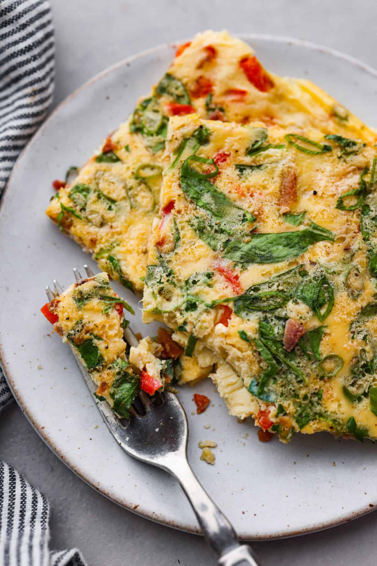 Sheet pan eggs are not only fluffy and full of flavor, but the best way to meal prep eggs or feed a crowd! Add your favorite mix-ins and serve as-is or use them to make breakfast sandwiches or as a topping for avocado toast! 2 servings of sheet pan eggs on a white plate.