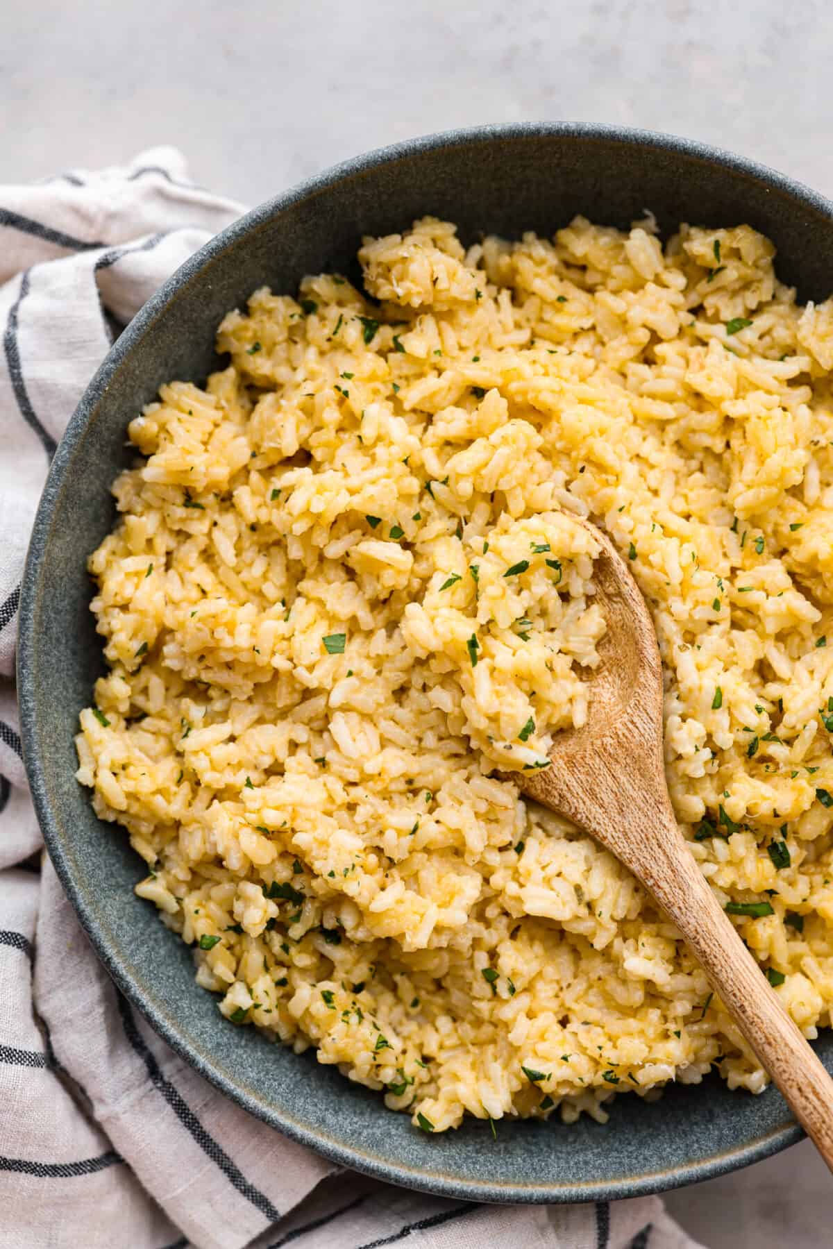 Make mealtime a breeze with this easy Souper Rice recipe! Combine creamy chicken soup, instant white rice, Parmesan cheese, and Italian seasonings for a quick and tasty dish. Simple, delicious, and a side dish that is ready in no time! A bowl filled with super rice and a wooden spoon.