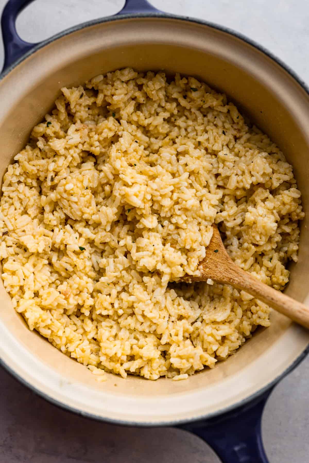 Make mealtime a breeze with this easy Souper Rice recipe! Combine creamy chicken soup, instant white rice, Parmesan cheese, and Italian seasonings for a quick and tasty dish. Simple, delicious, and a side dish that is ready in no time! Souper rice cooked and ready to eat in a pot with a wooden spoon.
