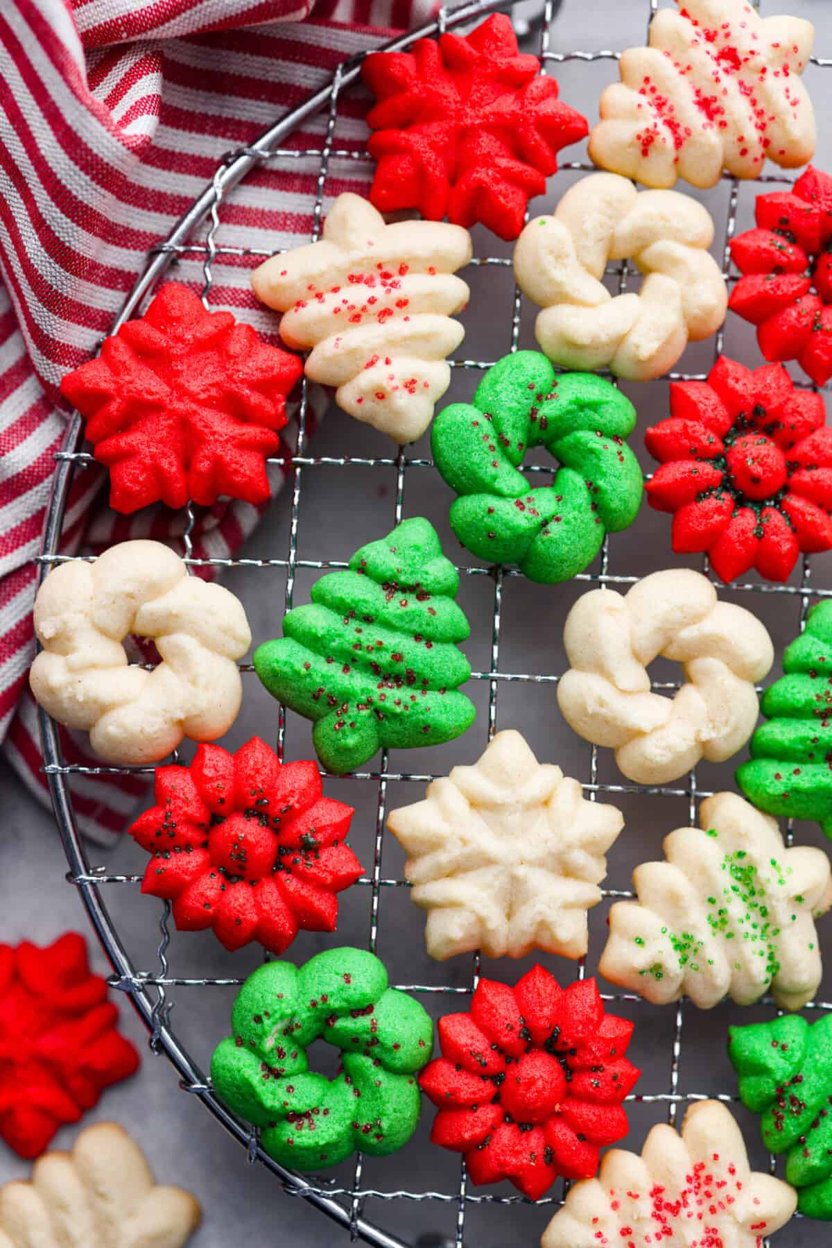 Spritz cookies are buttery and delicious, made with a cookie press to create festive shapes! Perfect for adding to any holiday dessert spread. Closeup of spritz cookies on a cooling rack.