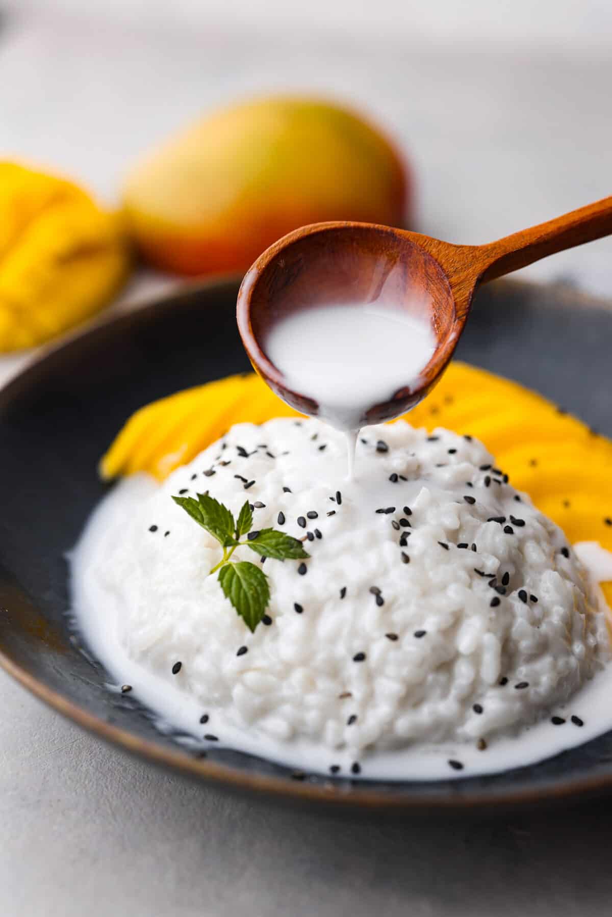 Dive into this irresistible mango sticky rice! Warm coconut sauce, fluffy rice, and juicy mangoes - an iconic Thai dessert made with love in your own home. Pouring the coconut sauce over the mango sticky rice.