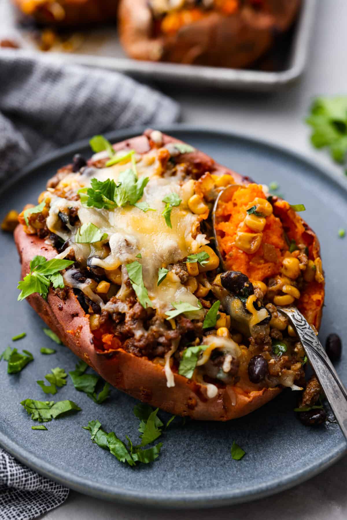 All your favorite taco fixings stuffed inside soft, tender sweet potatoes. This is a hearty, delicious dinner the whole family will love! It's meaty, cheesy, and extremely satisfying. Closeup of a stuffed sweet potato.