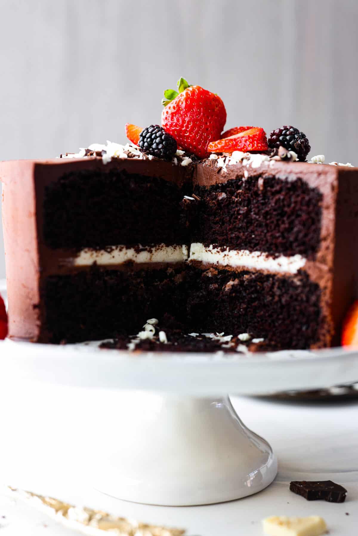 Chocolate lovers, this tuxedo cake is for you! Two layers of moist chocolate cake wrapped in chocolate and white chocolate ganache. So rich and delicious, it's almost sinful. A tuxedo cake with a slice cut out of it. The white chocolate ganache filling on the inside can be seen.