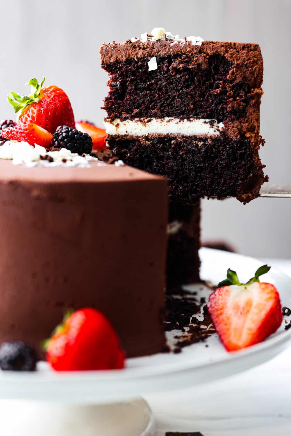 Chocolate lovers, this tuxedo cake is for you! Two layers of moist chocolate cake wrapped in chocolate and white chocolate ganache. So rich and delicious, it's almost sinful. Lifting a slice of tuxedo cake up with a metal spatula.