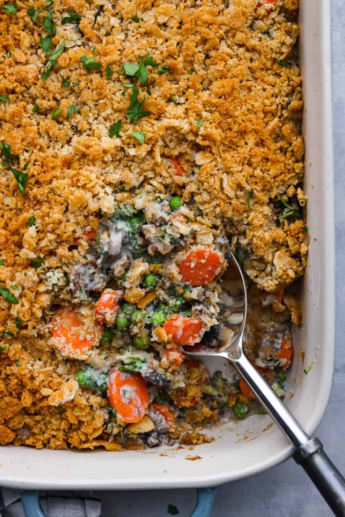 Delicious Vegetable Casserole is wonderfully creamy, flavorful and loaded up with tender broccoli florets, carrots, mushrooms and peas. It's topped with crispy buttered Ritz cracker crumbs, and baked to golden brown perfection. A dish that's sure to be the highlight of your dinner! Closeup of vegetable casserole.