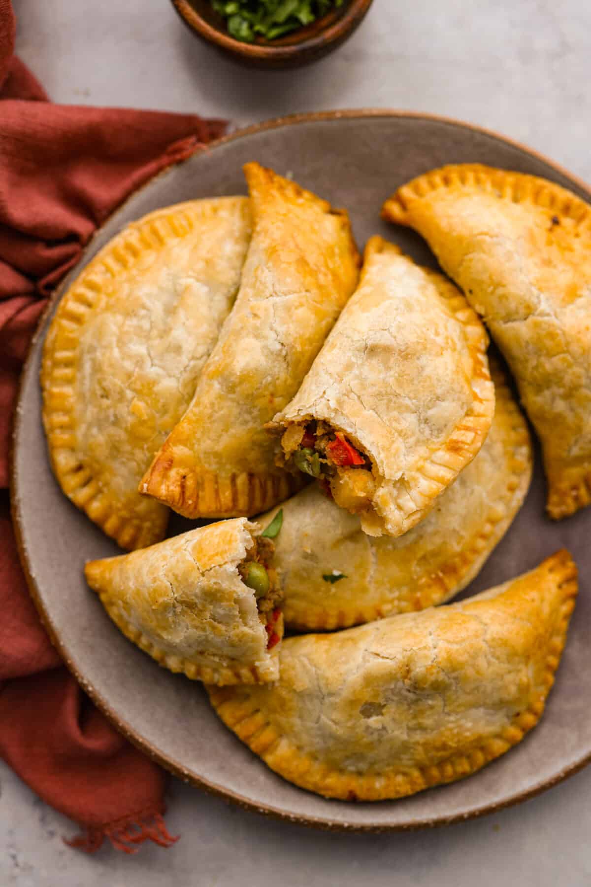 Empanadas made easy by cooking them in the air fryer and using premade pie crusts for the dough! Top-down view of the empanadas on a serving dish.