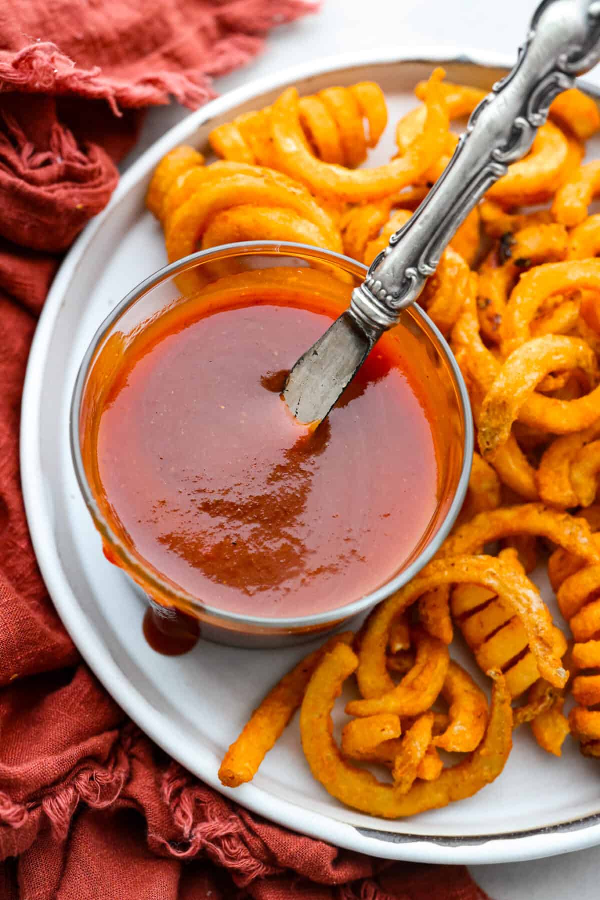 Skip the drive-thru and whip up this irresistible homemade Arby's sauce in minutes! It's a delicious mix of smoky paprika, tangy vinegar, and brown sugar. Curly fries served with Arby’s sauce in a small glass bowl.