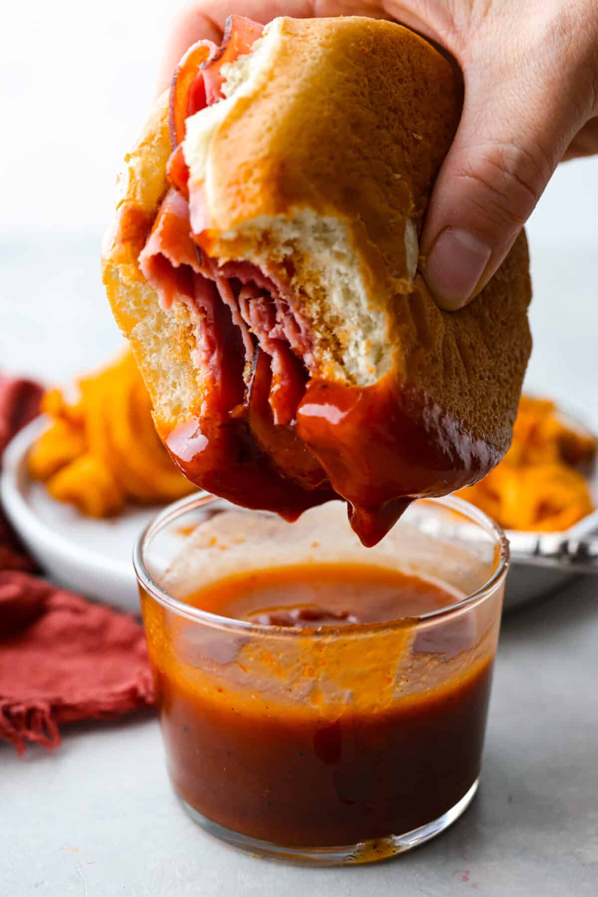 Skip the drive-thru and whip up this irresistible homemade Arby's sauce in minutes! It's a delicious mix of smoky paprika, tangy vinegar, and brown sugar. Dipping a sandwich with a bite taken out of it into the Arby’s sauce.