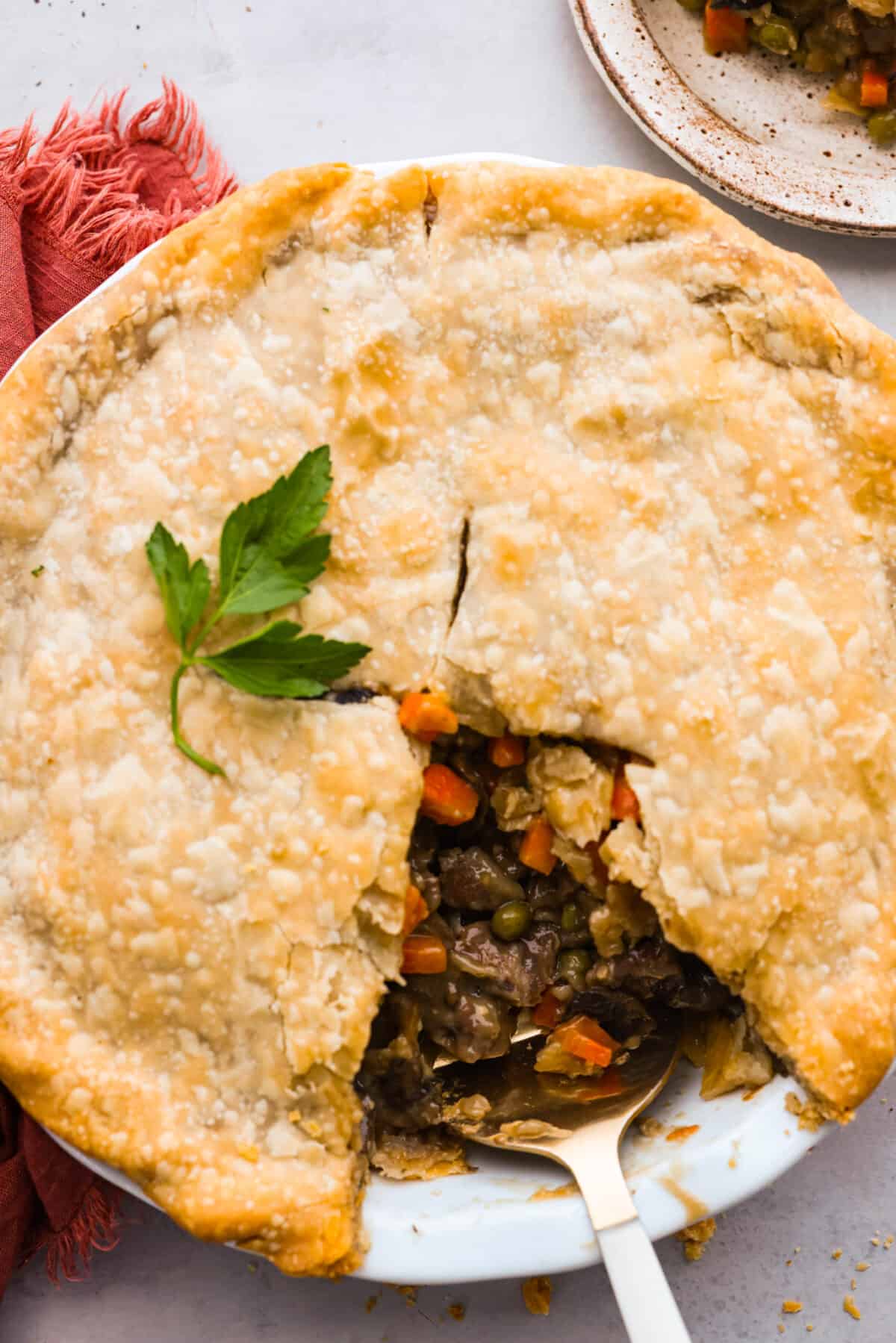 Classic comfort food with a homemade twist! This hearty beef pot pie features tender chunks of beef, savory veggies, and a rich gravy all nestled in a flaky double crust! (You can use store-bought crusts for easy prep!) Top-down view of beef pot pie with a slice taken out of it.