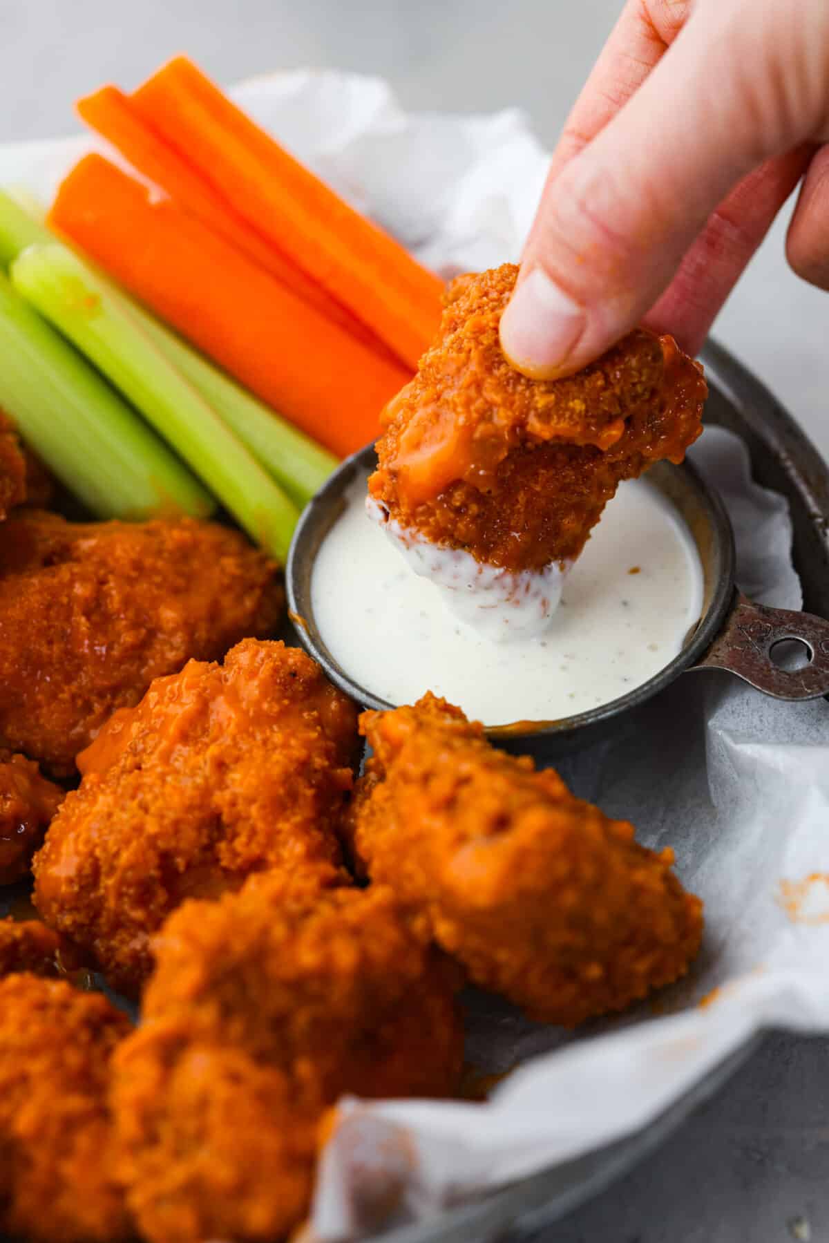 If youโre still working on your Super Bowl food lineup, add these amazing boneless wings to the list! They have a crispy buttermilk breading and are tossed in a mouthwatering buffalo sauce. Dipping a buffalo wing into ranch dressing.