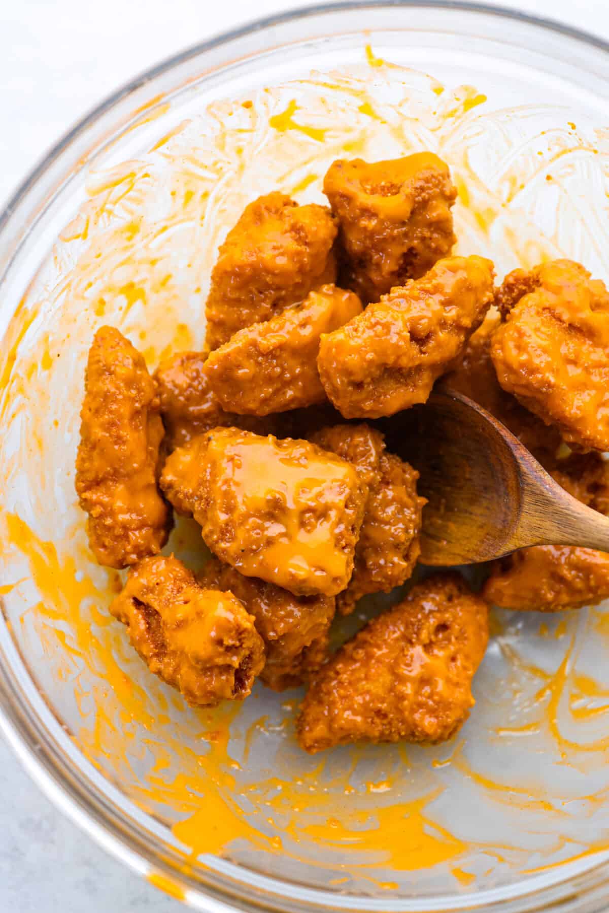 If youโre still working on your Super Bowl food lineup, add these amazing boneless wings to the list! They have a crispy buttermilk breading and are tossed in a mouthwatering buffalo sauce. Coating the boneless wings in buffalo sauce.