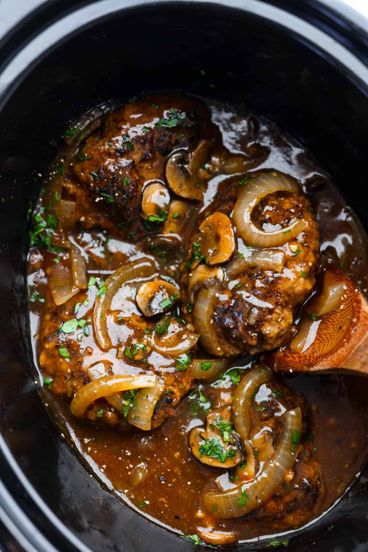 Make dinnertime easy with this Crockpot Salisbury Steak recipe! Juicy beef patties slow cooked to tender perfection in an onion and mushroom gravy. This is a no-fuss dinner that is so hearty and delicious! Salisbury Steaks in a slow cooker, covered with a mushroom and onion gravy.