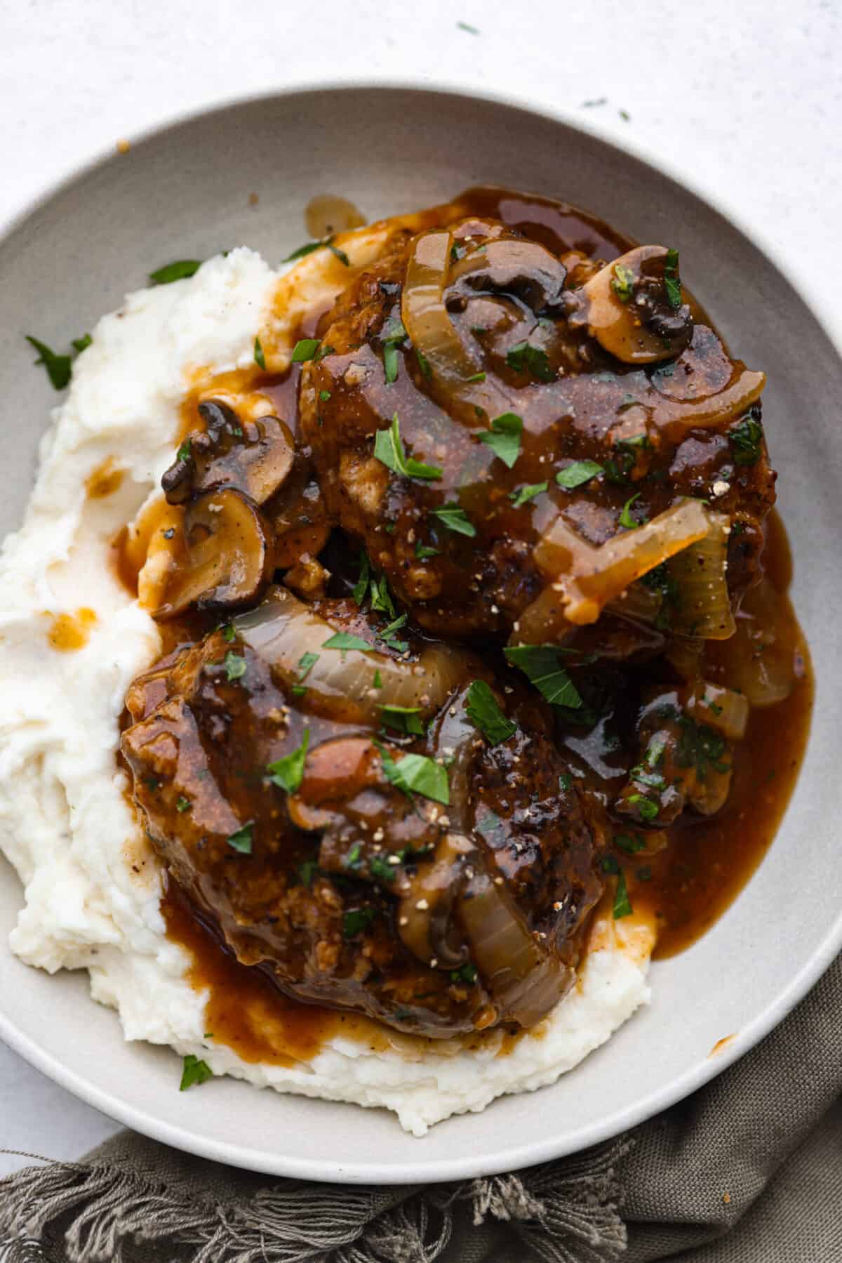 Make dinnertime easy with this Crockpot Salisbury Steak recipe! Juicy beef patties slow cooked to tender perfection in an onion and mushroom gravy. This is a no-fuss dinner that is so hearty and delicious! Crockpot Salisbury Steaks served over mashed potatoes.