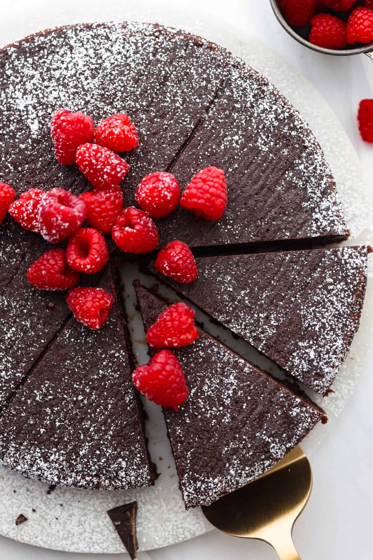Flourless Chocolate Cake is an insanely rich and delicious chocolate dessert.ย Similar to the inside of a truffle, this gluten-free dessert will satisfy your sweet tooth with ease! Top-down view of flourless chocolate cake cut into slices.