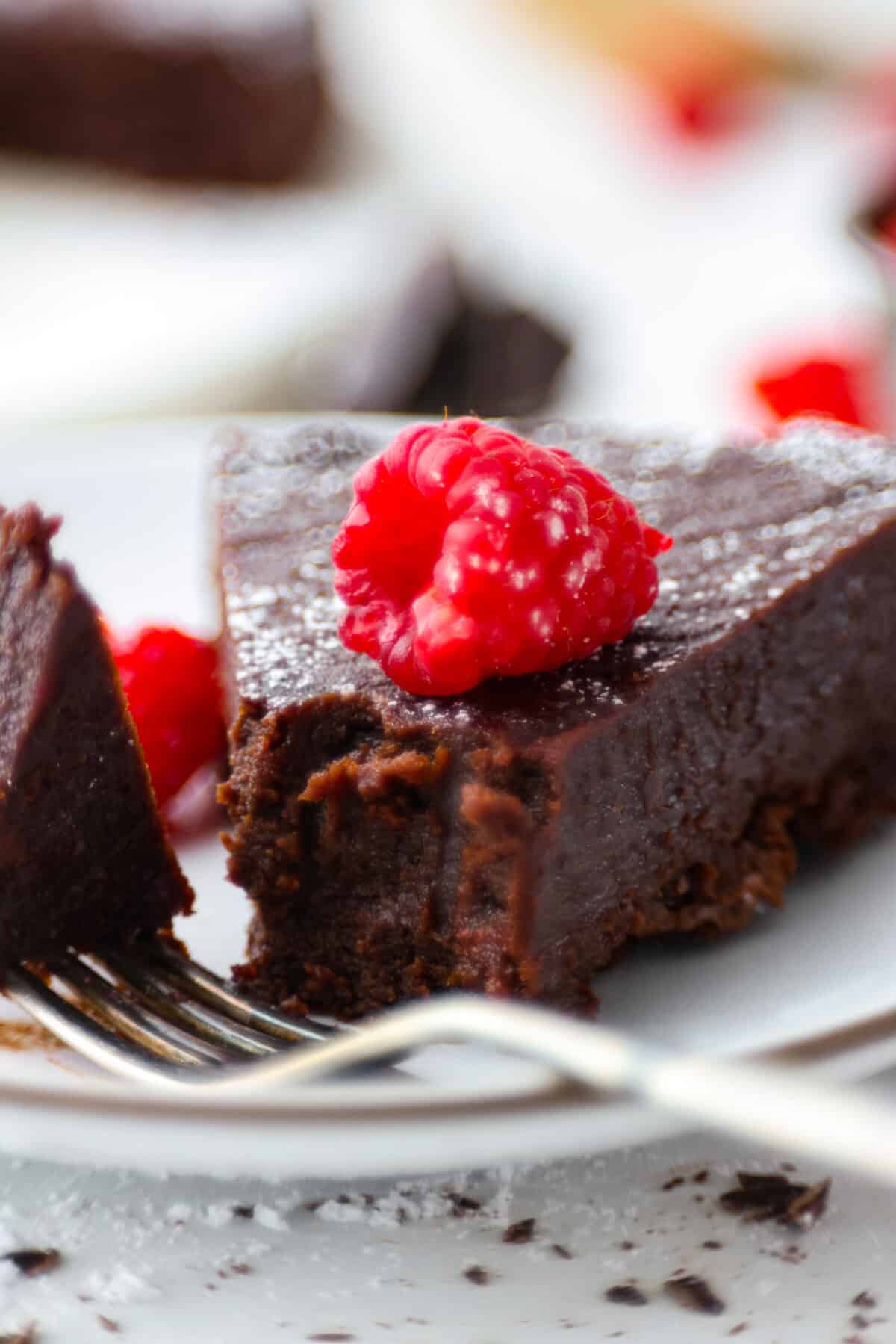 Flourless Chocolate Cake is an insanely rich and delicious chocolate dessert.ย Similar to the inside of a truffle, this gluten-free dessert will satisfy your sweet tooth with ease! A slice of cake with a bite taken out of it.