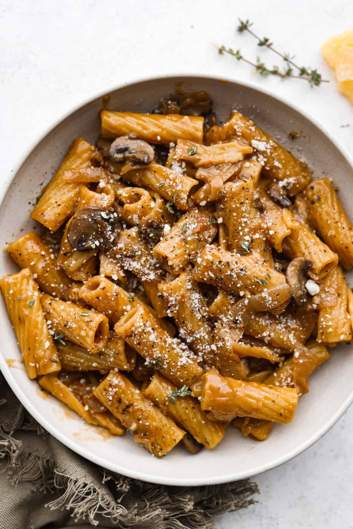 French Onion Pasta has all of the delicious flavors of the classic soup in pasta form! Caramelized onions, garlic, mushrooms, and thyme are combined with beef broth, pasta, Worcestershire sauce and parmesan cheese to create an incredible dish. French onion pasta in a white bowl.