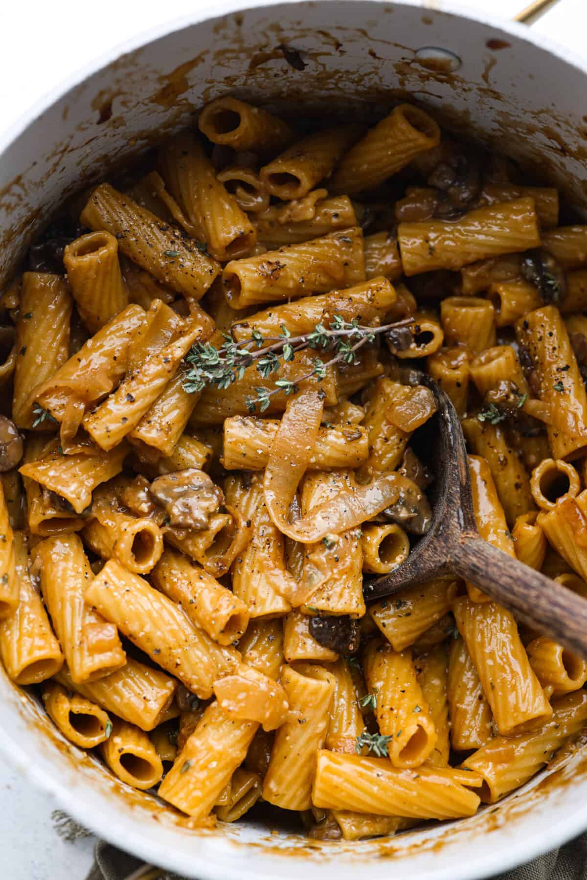 French Onion Pasta has all of the delicious flavors of the classic soup in pasta form! Caramelized onions, garlic, mushrooms, and thyme are combined with beef broth, pasta, Worcestershire sauce and parmesan cheese to create an incredible dish. Onion pasta in a white pot.