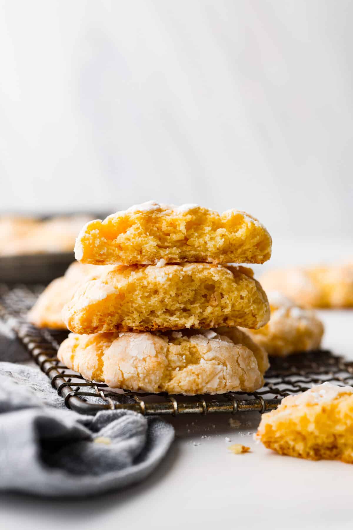 Rich, chewy, and topped with a dusting of powdered sugar, these gooey butter cookies are every cookie lover’s dream! You only need a handful of simple ingredients to make them. Give them a try and watch them fly off the table! 3 cookies stacked on top of each other. 2 are pieces that have been broken in half.