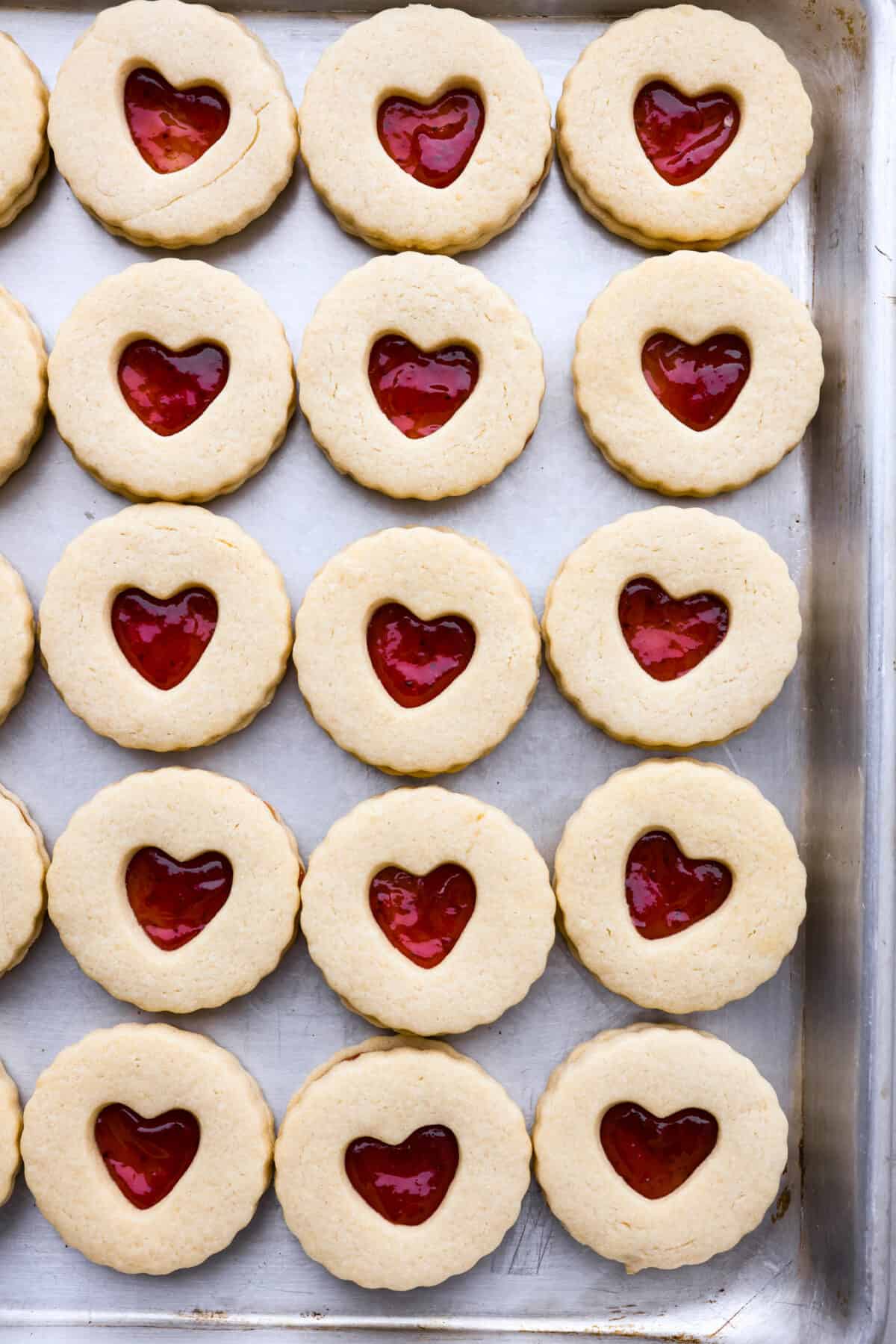 Adorable Jammie Dodgers feature tart strawberry jam sandwiched betweenย buttery shortbread cookies for a gorgeous treat that will be the star of any dessert spread! Top-down view of jammie dodgers in a baking sheet.