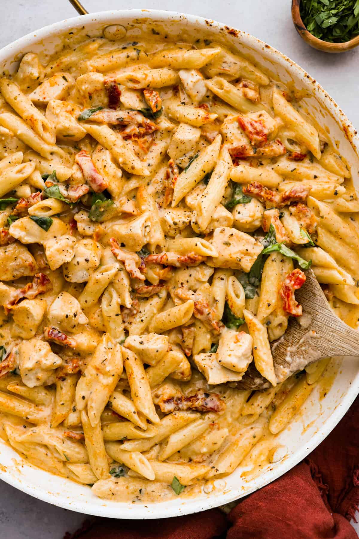 Reader-favorite ‘Marry Me Chicken’ made even better with tender penne pasta! The noodles hold the cheesy, sun-dried tomato sauce inside for a burst of flavor in each bite! It’s sure to win over anyone that tries it. Top-down view of marry me chicken pasta in a white skillet.