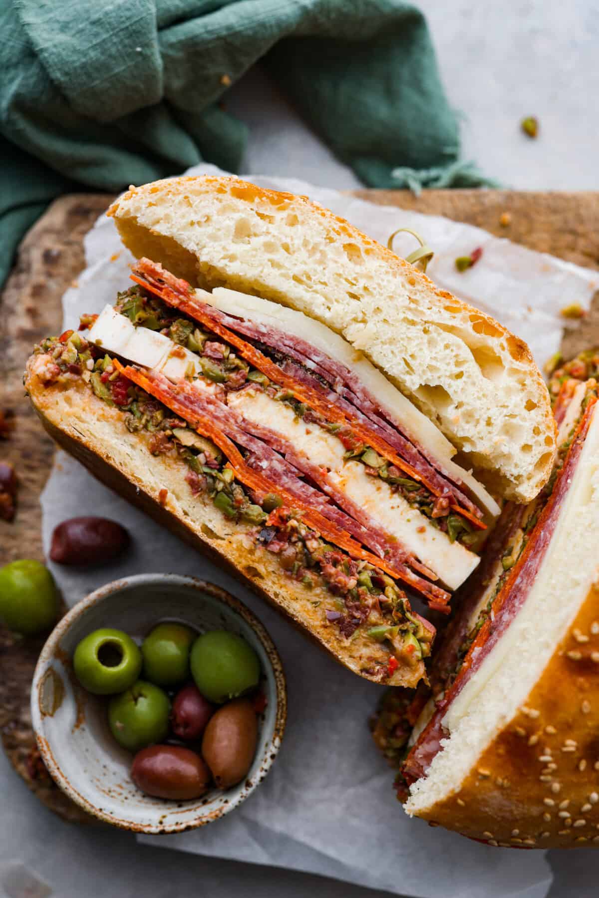 The Muffuletta is an iconic sandwich from New Orleans that is piled high with layers of meat, cheese and a delicious olive salad! Served on either Italian bread or muffuletta bread, youโll be obsessed after the first bite! One half of a muffuletta sandwich. The meat and cheese filling can be seen.