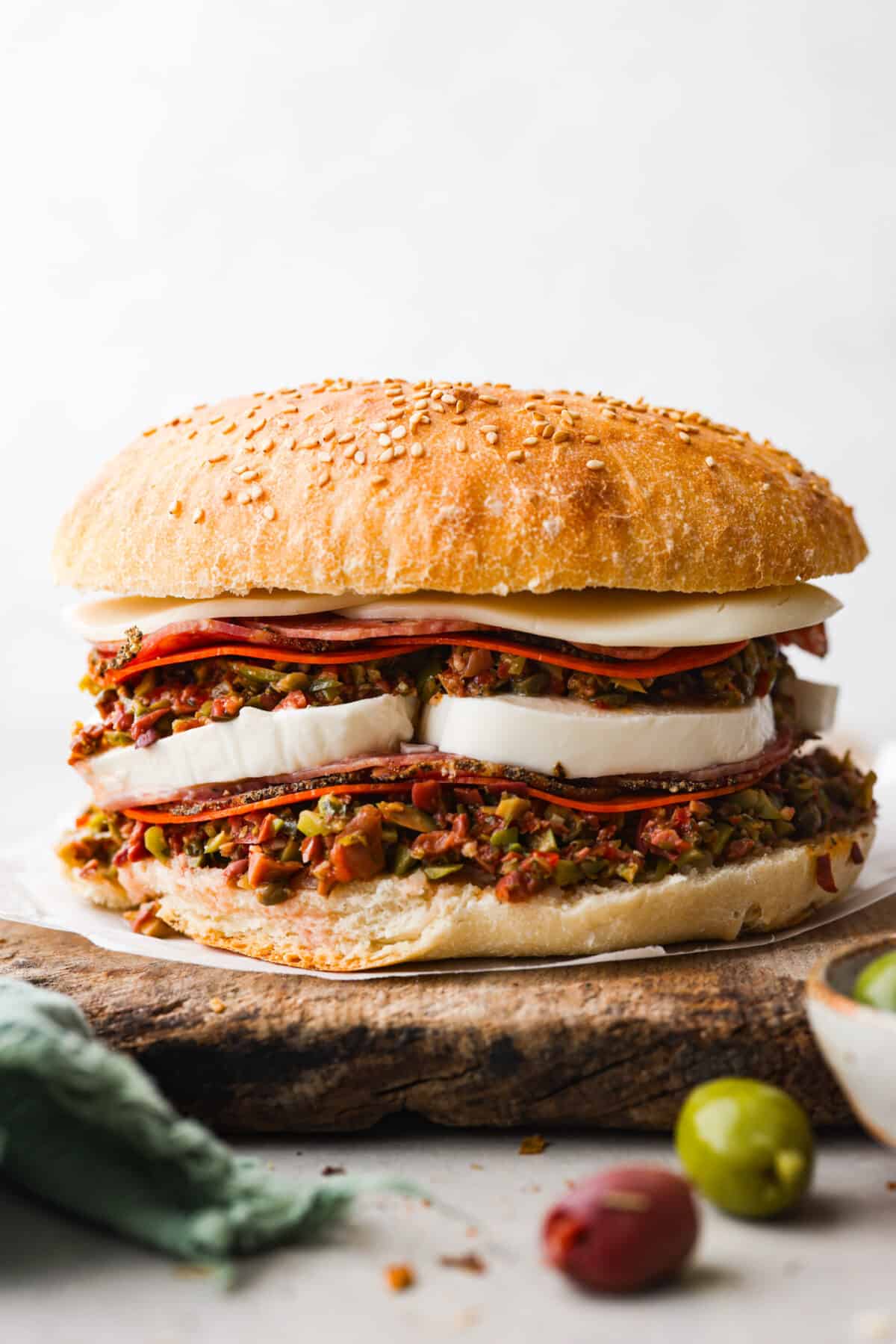 The Muffuletta is an iconic sandwich from New Orleans that is piled high with layers of meat, cheese and a delicious olive salad! Served on either Italian bread or muffuletta bread, youโll be obsessed after the first bite! Hero image of a muffuletta sandwich.