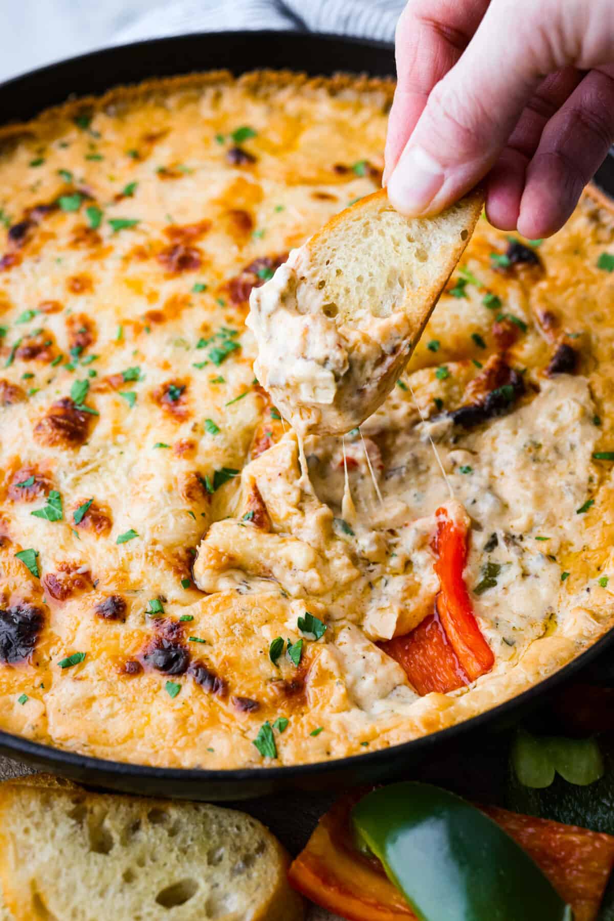 Craving a Philly cheesesteak but want something dippable and shareable? Skip the sandwich and whip up this Philly Cheesesteak Dip instead. It's bursting with tender roast beef and savory spices, all in a creamy, cheesy base. A must-make appetizer for any occasion! Dipping into the Philly cheesesteak dip with crostini.