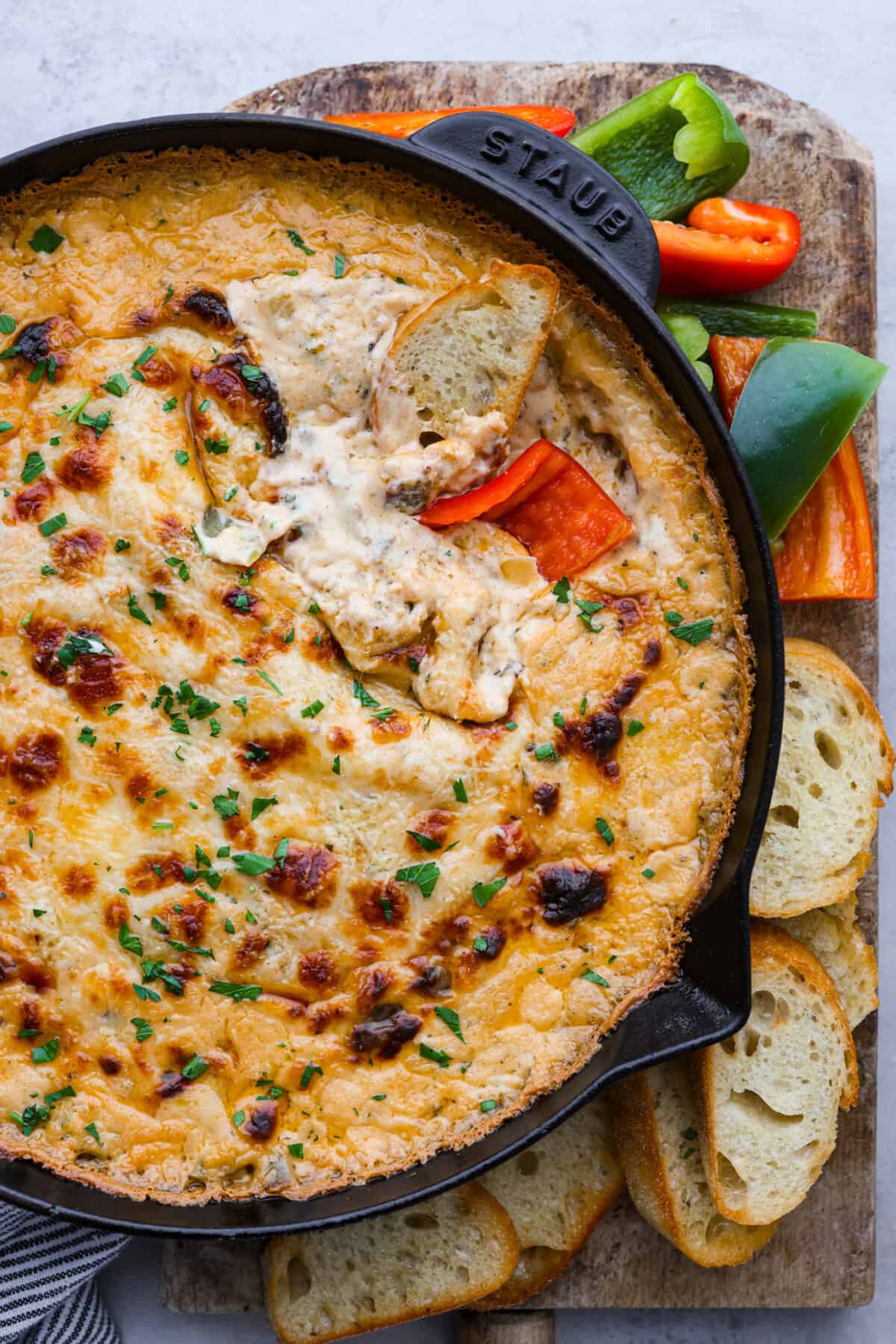 Craving a Philly cheesesteak but want something dippable and shareable? Skip the sandwich and whip up this Philly Cheesesteak Dip instead. It's bursting with tender roast beef and savory spices, all in a creamy, cheesy base. A must-make appetizer for any occasion! Philly cheesesteak served on a board with vegetables and sliced pieces of bread.