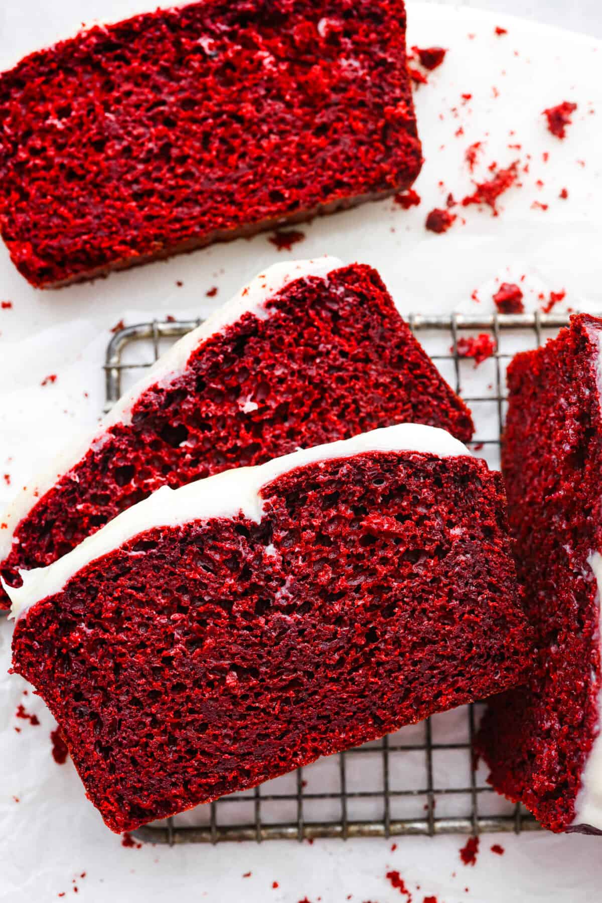 Fall in love with this perfectly moist red velvet pound cake with a cream cheese glaze! With its signature red color and the subtle chocolate flavor, this pound cake is easy to make and irresistibly delicious! Top view of the sliced pound cake on a cooling rack.