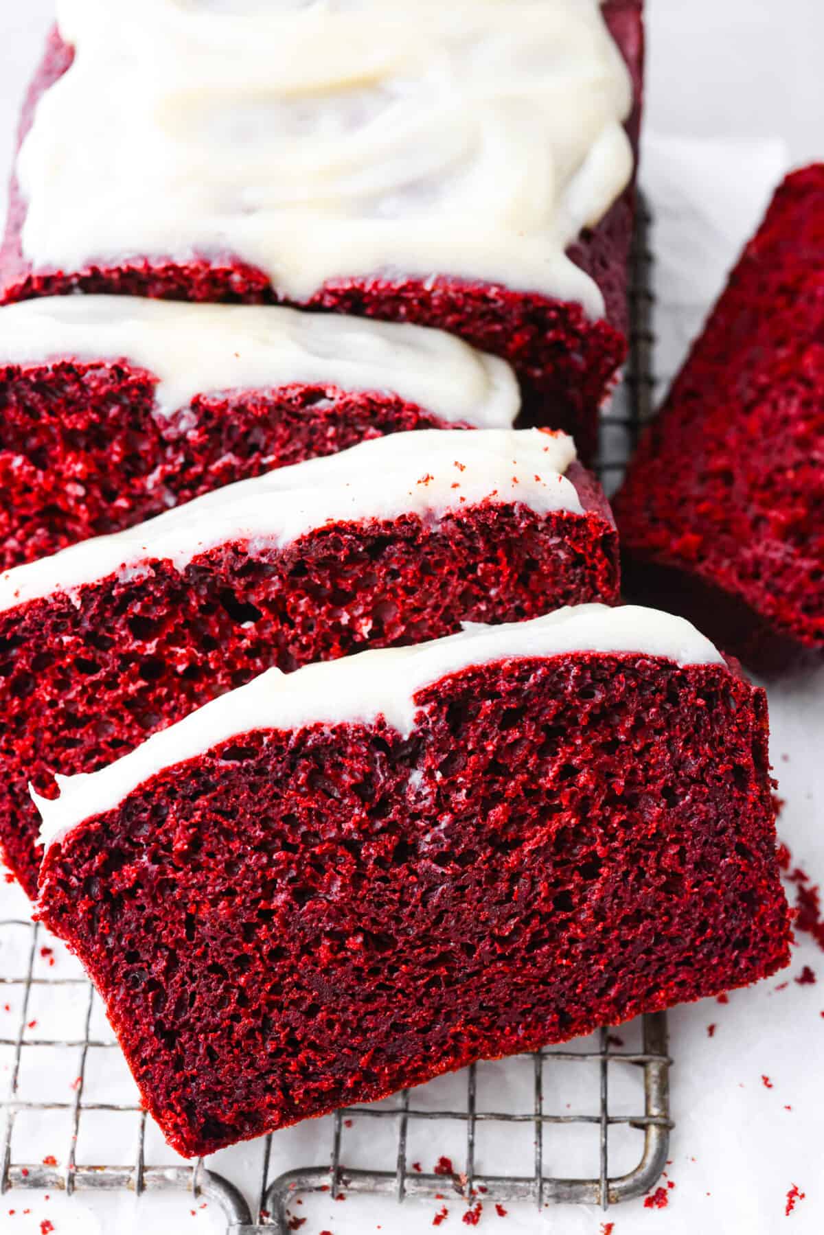 Fall in love with this perfectly moist red velvet pound cake with a cream cheese glaze! With its signature red color and the subtle chocolate flavor, this pound cake is easy to make and irresistibly delicious! Close view of red velvet pound cake sliced with cream cheese glaze on top.