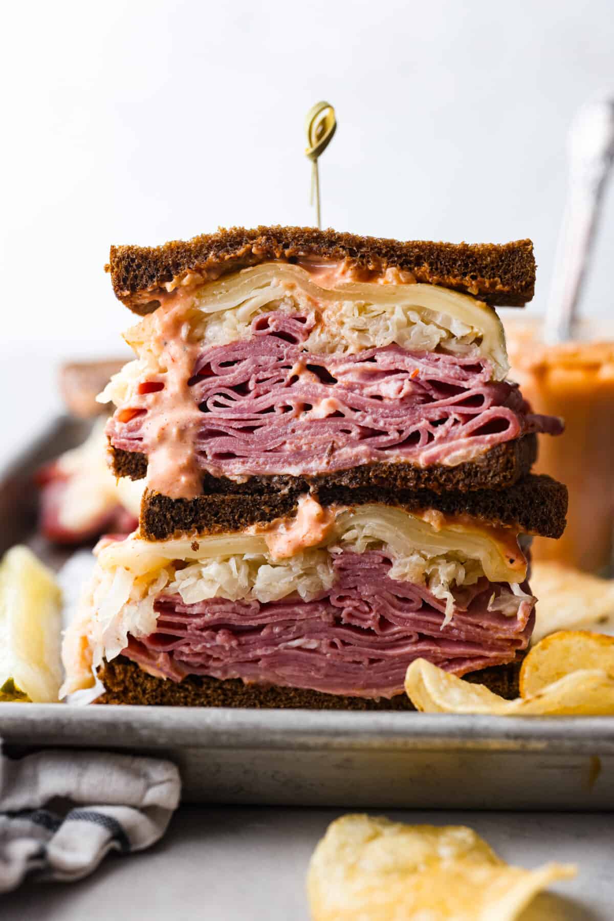 This incredible Reuben Sandwich is stuffed to the brim on rye bread with layers of thinly sliced corned beef, plenty of Swiss cheese, sauerkraut, and dressing. Broiled until the cheese is melty and everything is warm and flavorful, this is one epic sandwich! 2 reuben sandwich slices, stacked on top of each other.